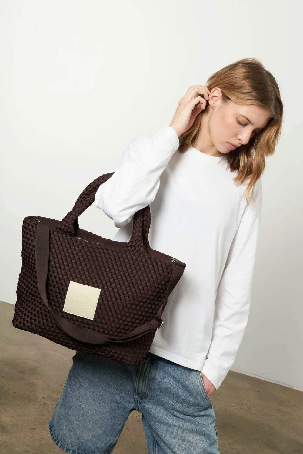 Woman holding a brown textured bag against a plain background