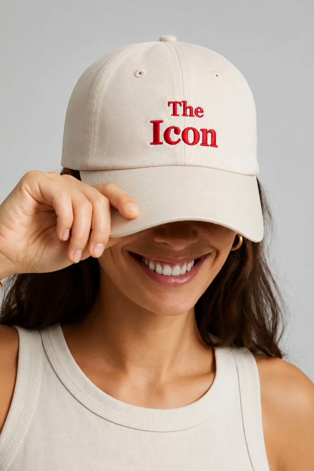 An off-white baseball cap with 'The Icon' embroidered in red on the front, set against a neutral gray background.
