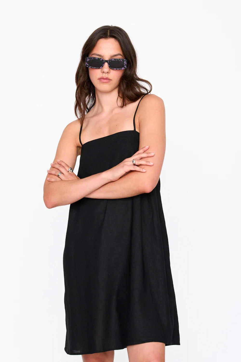 Woman wearing a black dress and sunglasses on a white background