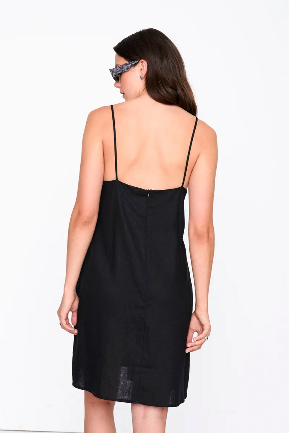 Woman wearing a black slip dress on a white background