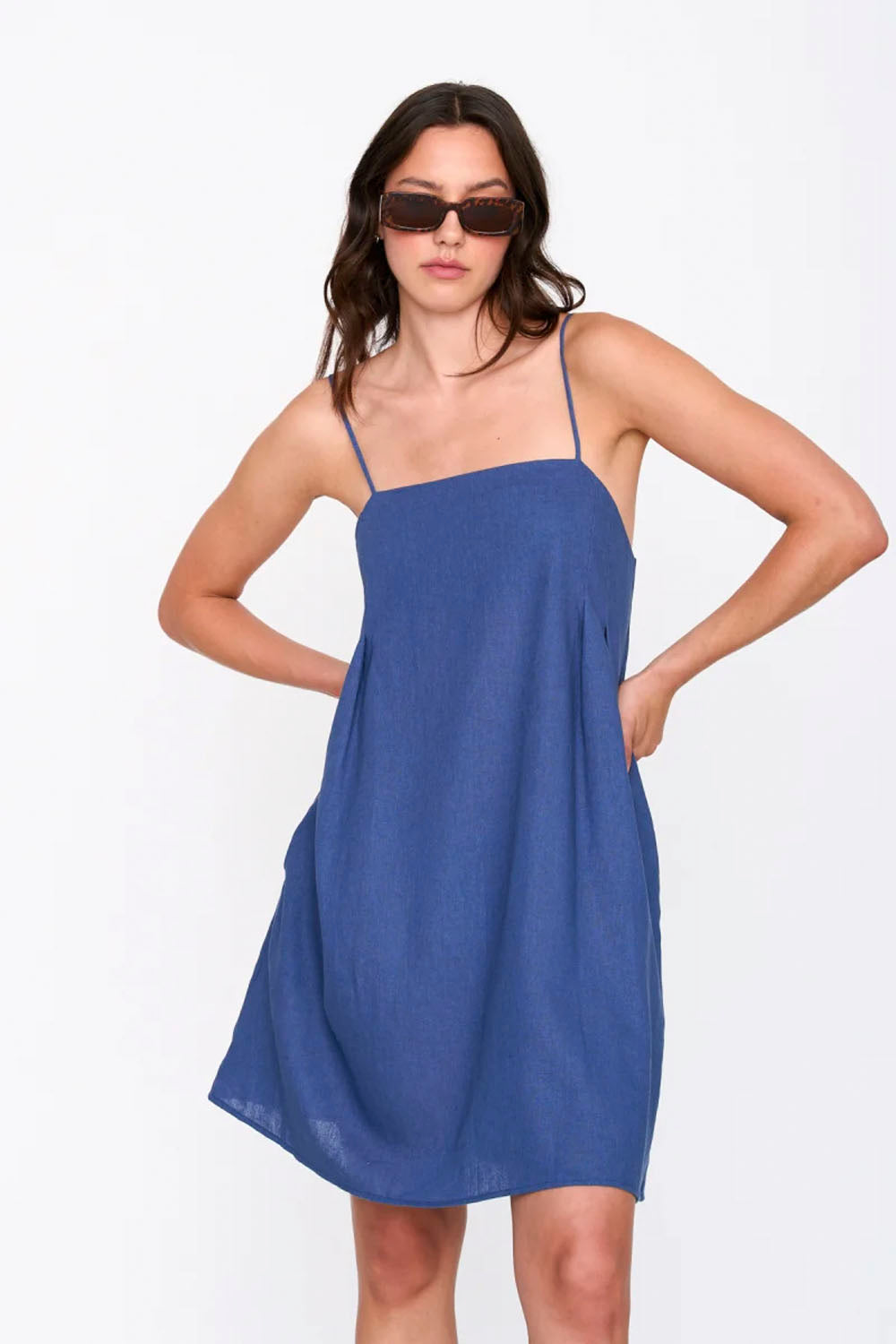 Woman wearing a blue slip dress on a white background