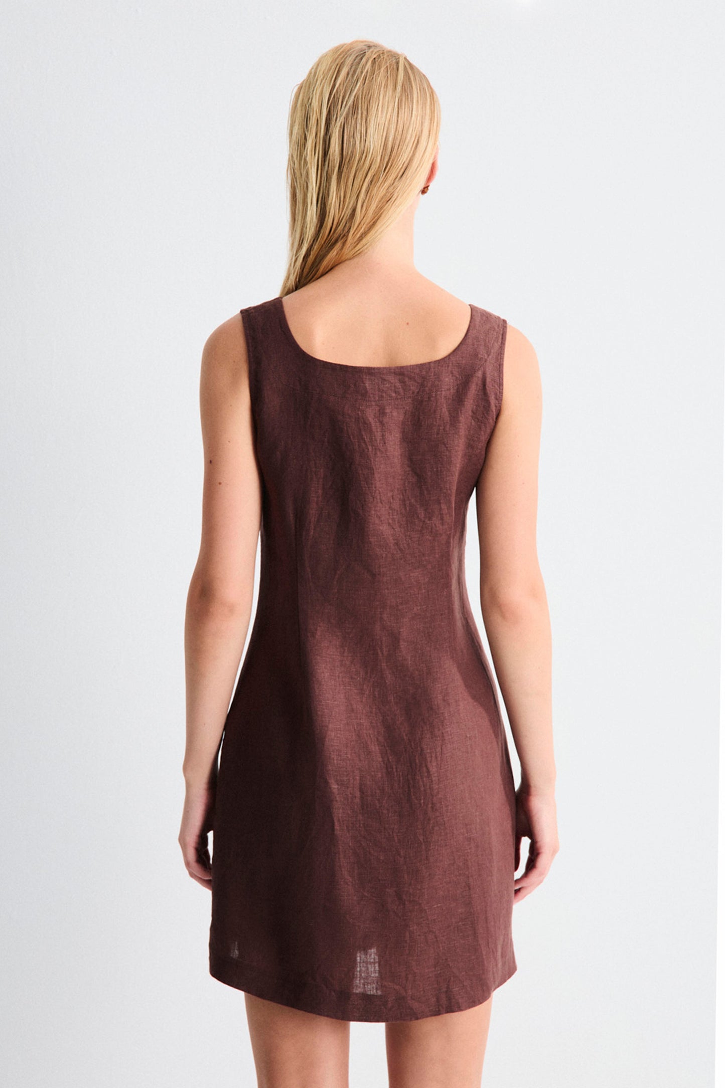 Woman wearing a brown sleeveless dress on a white background