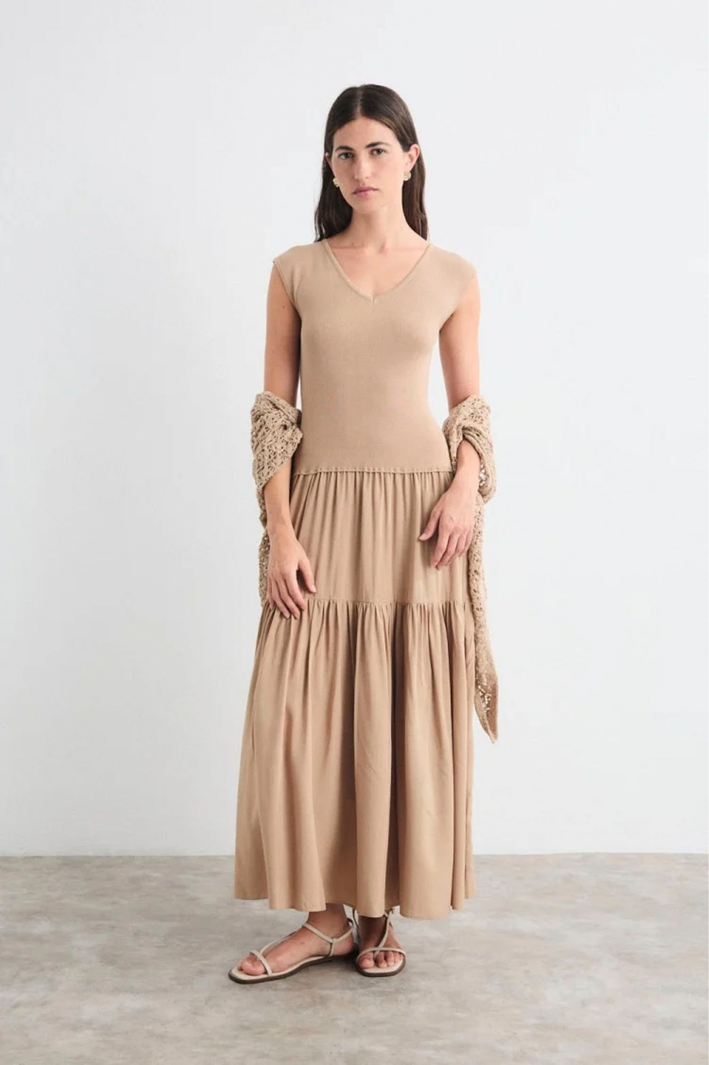 Woman wearing a beige dress with ruffled sleeves against a white background