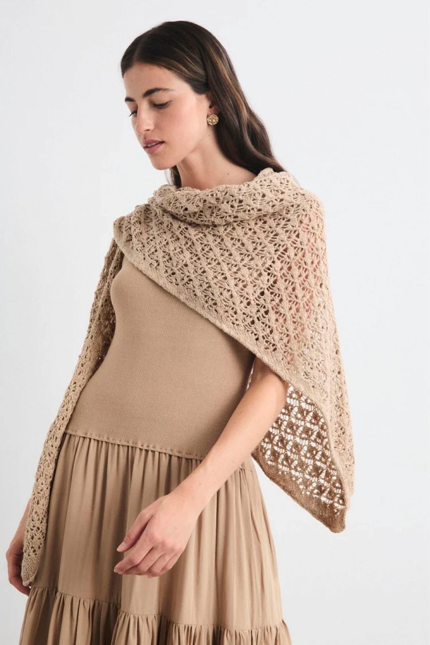 Woman wearing a beige shawl over a dress on a white background