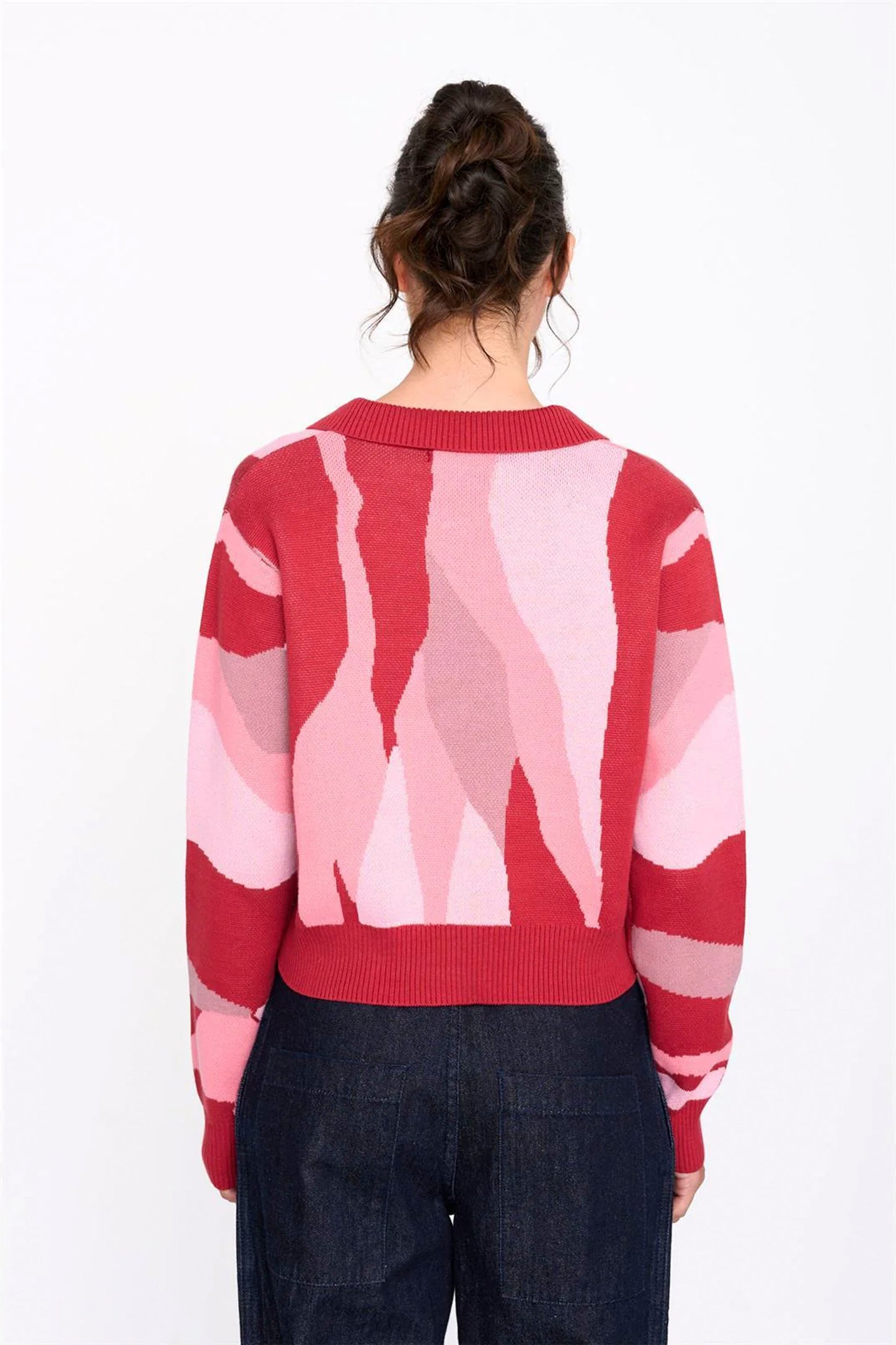 Person wearing a red and pink patterned sweater on a white background