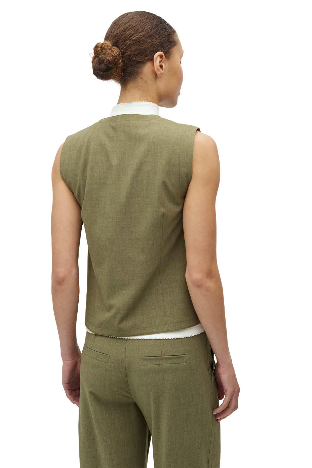 Woman wearing a green sleeveless top and pants on a white background