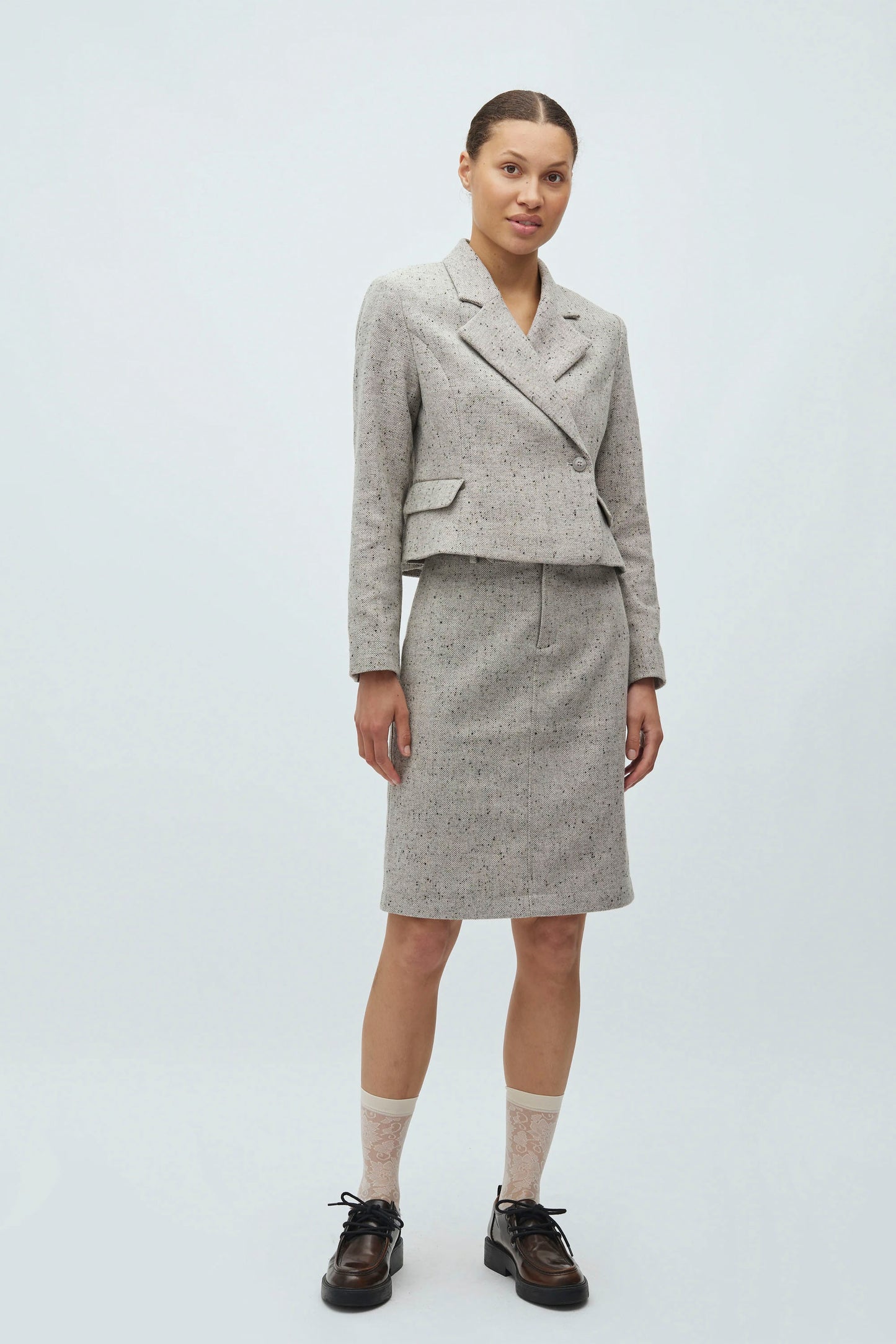 Woman wearing grey mbyM Iva blazer on a white background