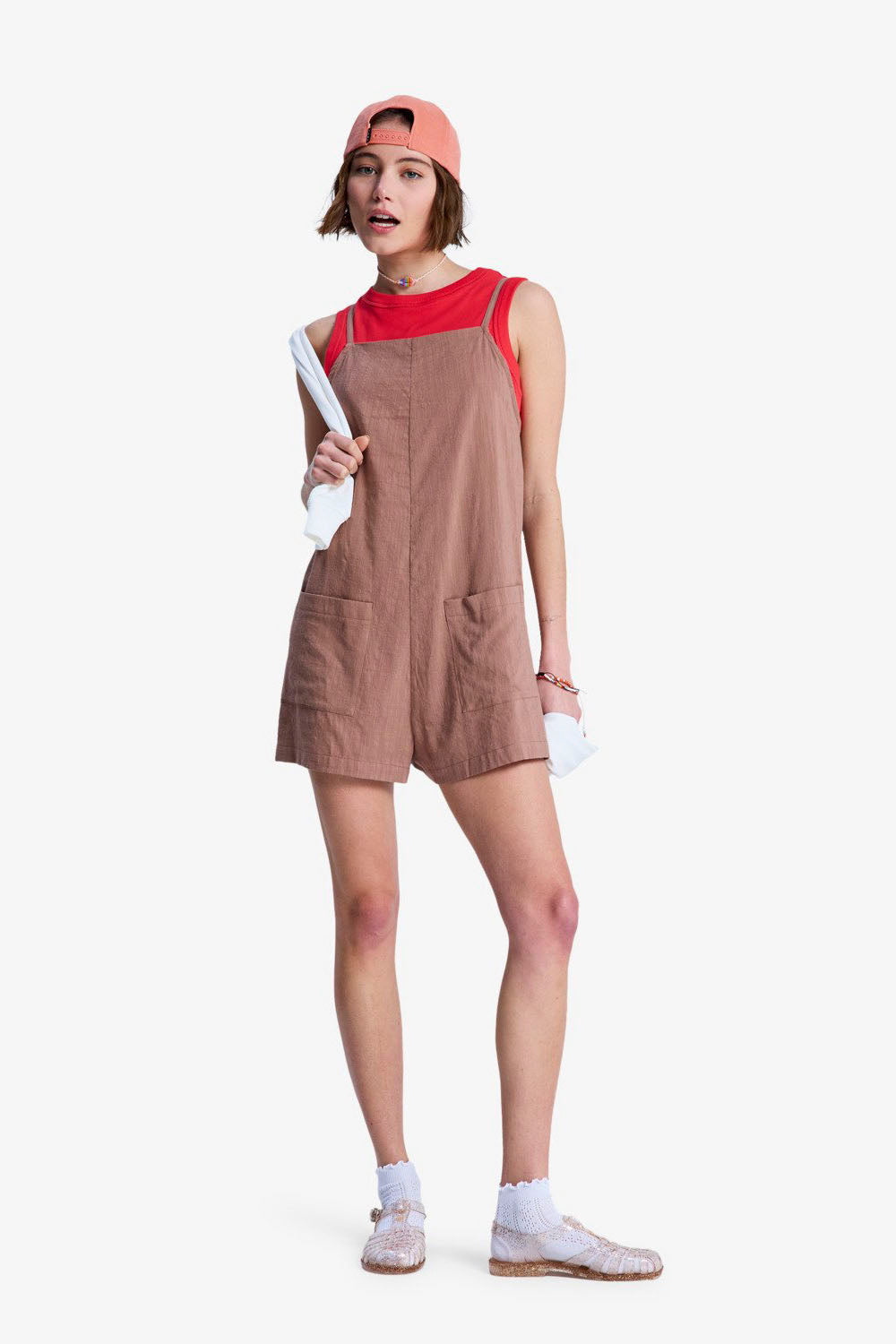 Person wearing a brown Roxy Lavender Haze Romper pinafore dress over a red top on a white background