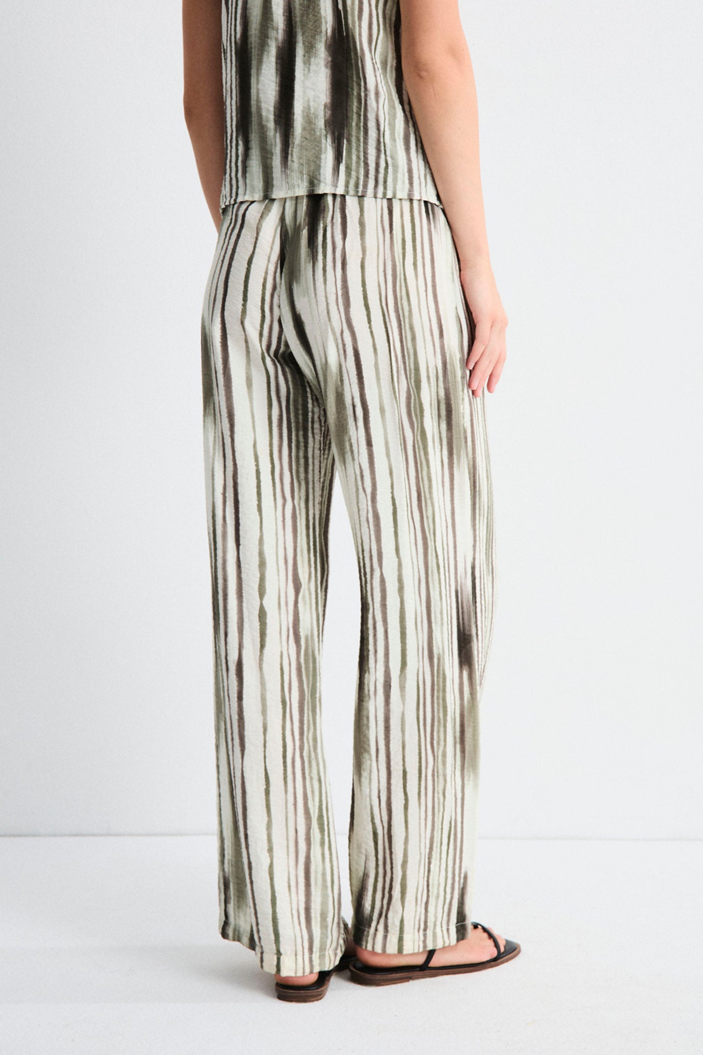 Person wearing a sleeveless top and wide-leg pants with a striped pattern on a white background
