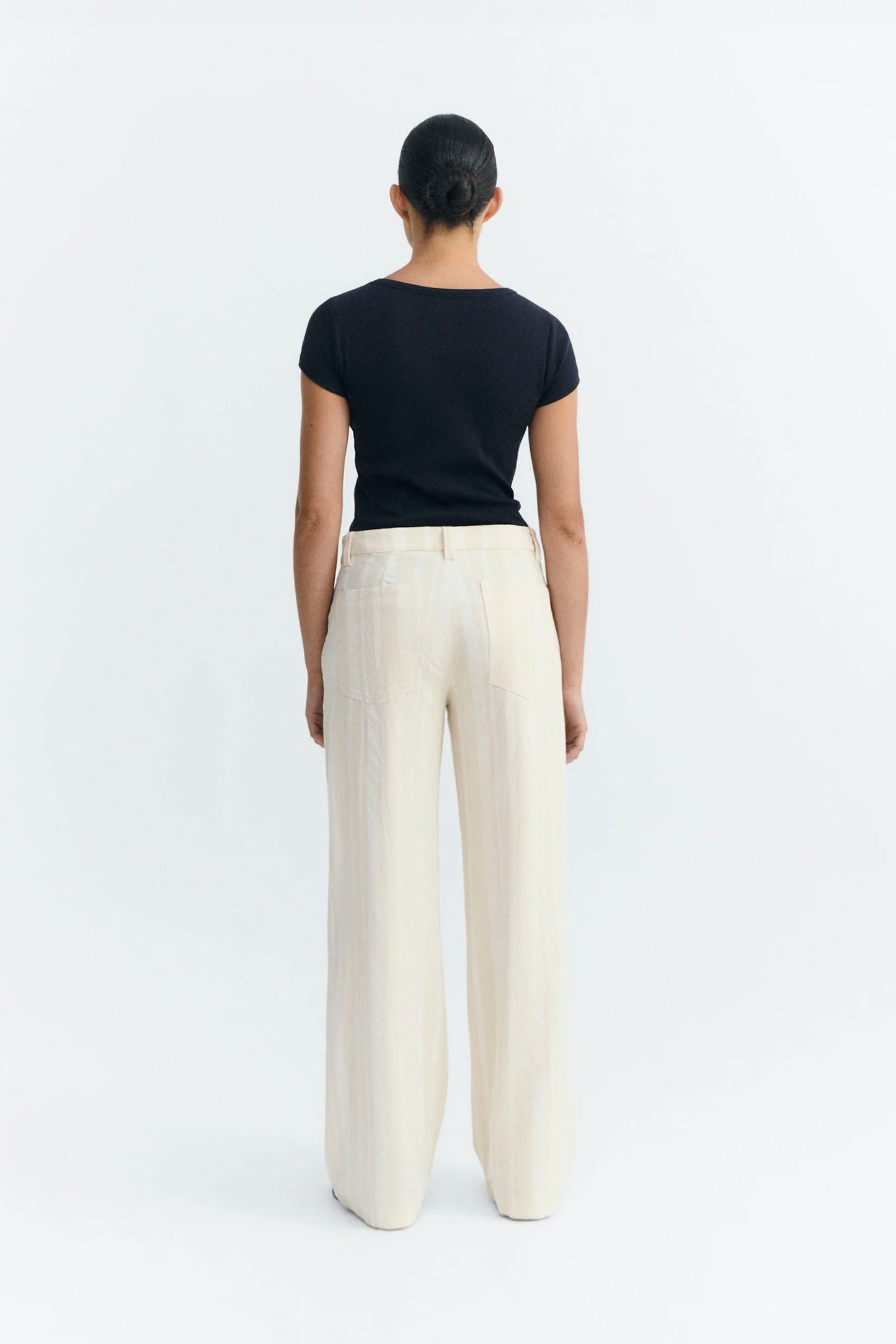 Person wearing a black top and white Thinking Mu pants on a white background