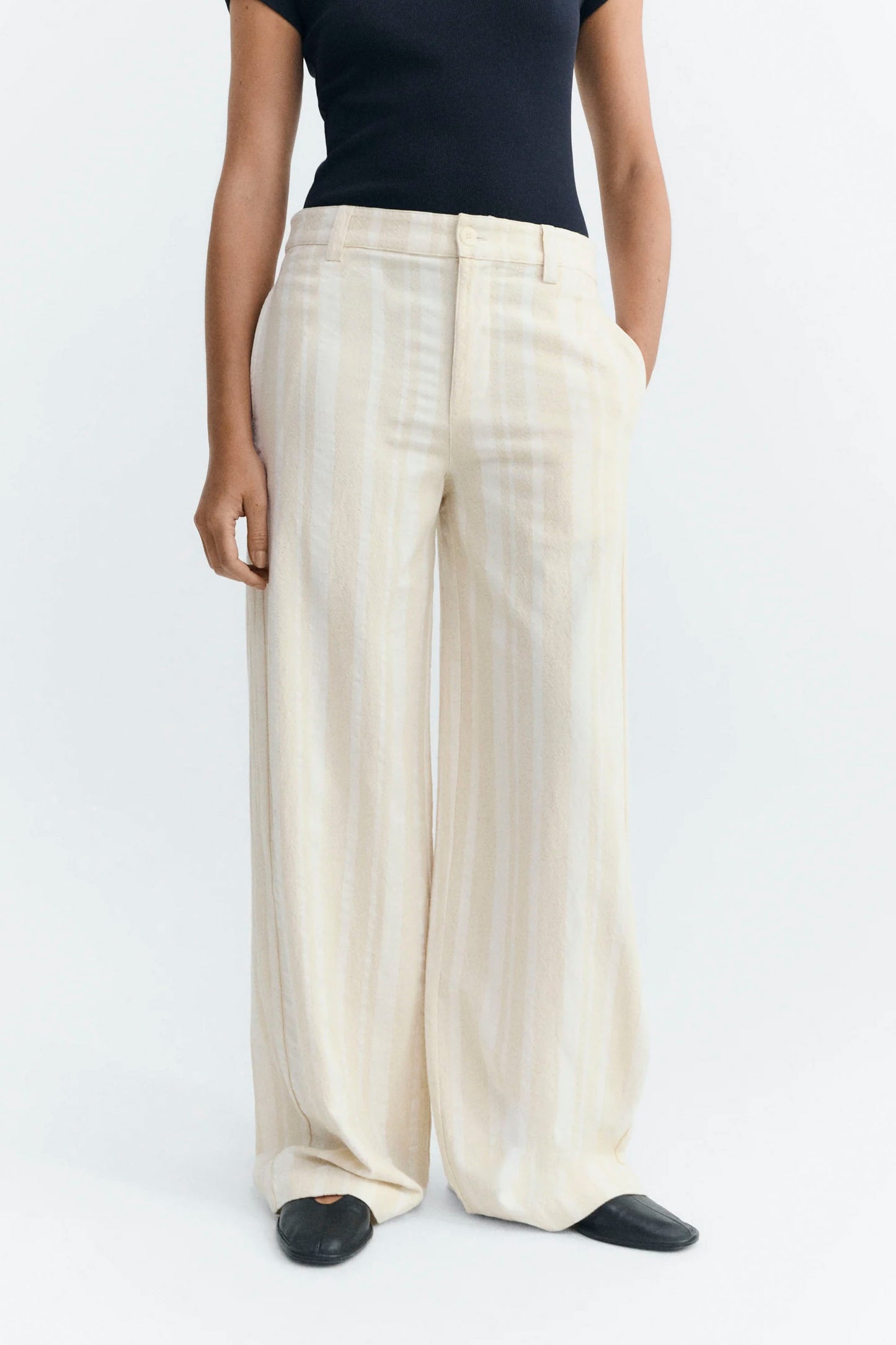 Person wearing white Thinking Mu wide-leg pants and a black top on a white background