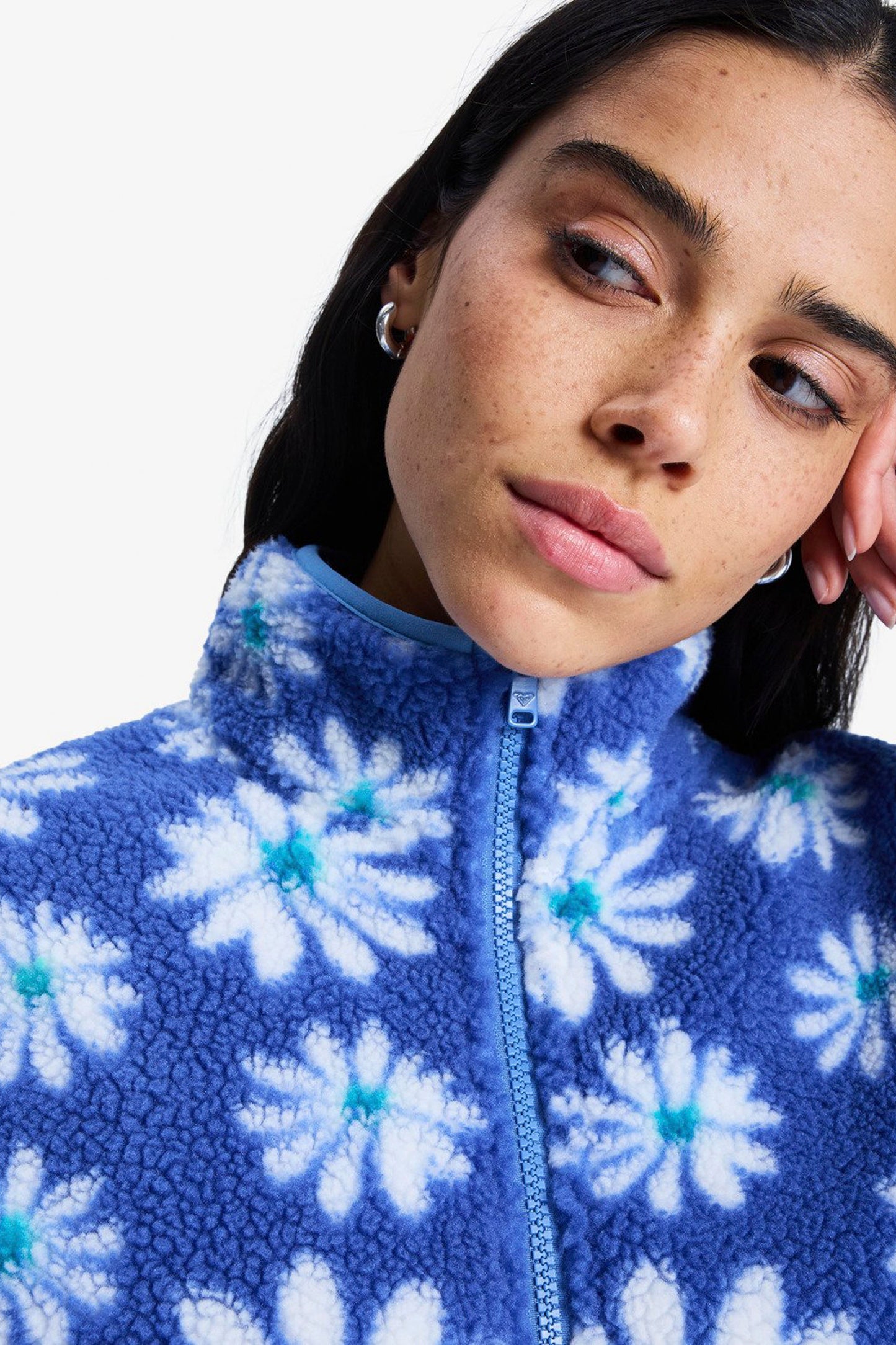 Person wearing a blue fleece jacket with white floral patterns on a plain background