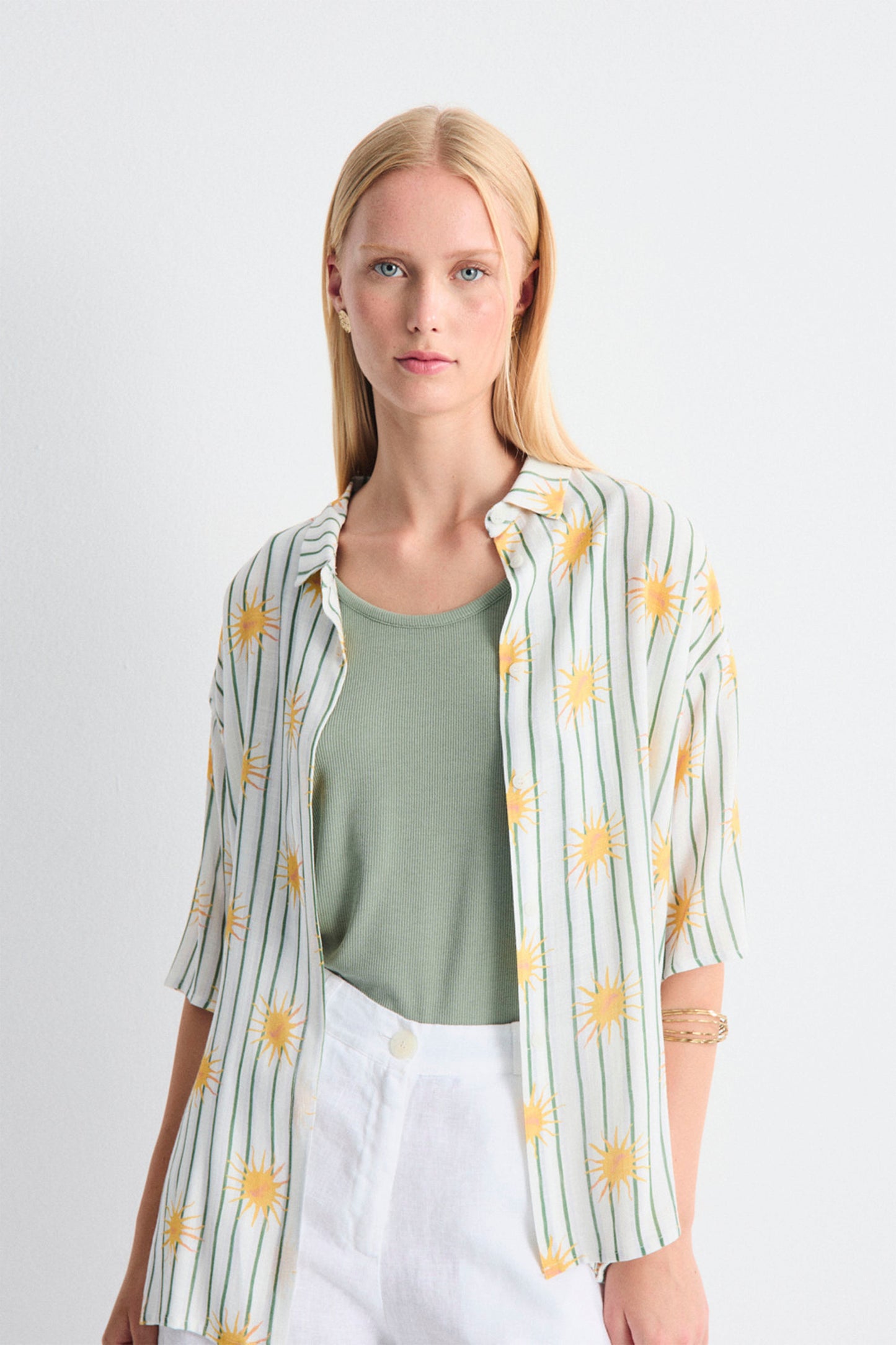 Woman wearing a light green shirt with a colorful pattern over a green top on a white background