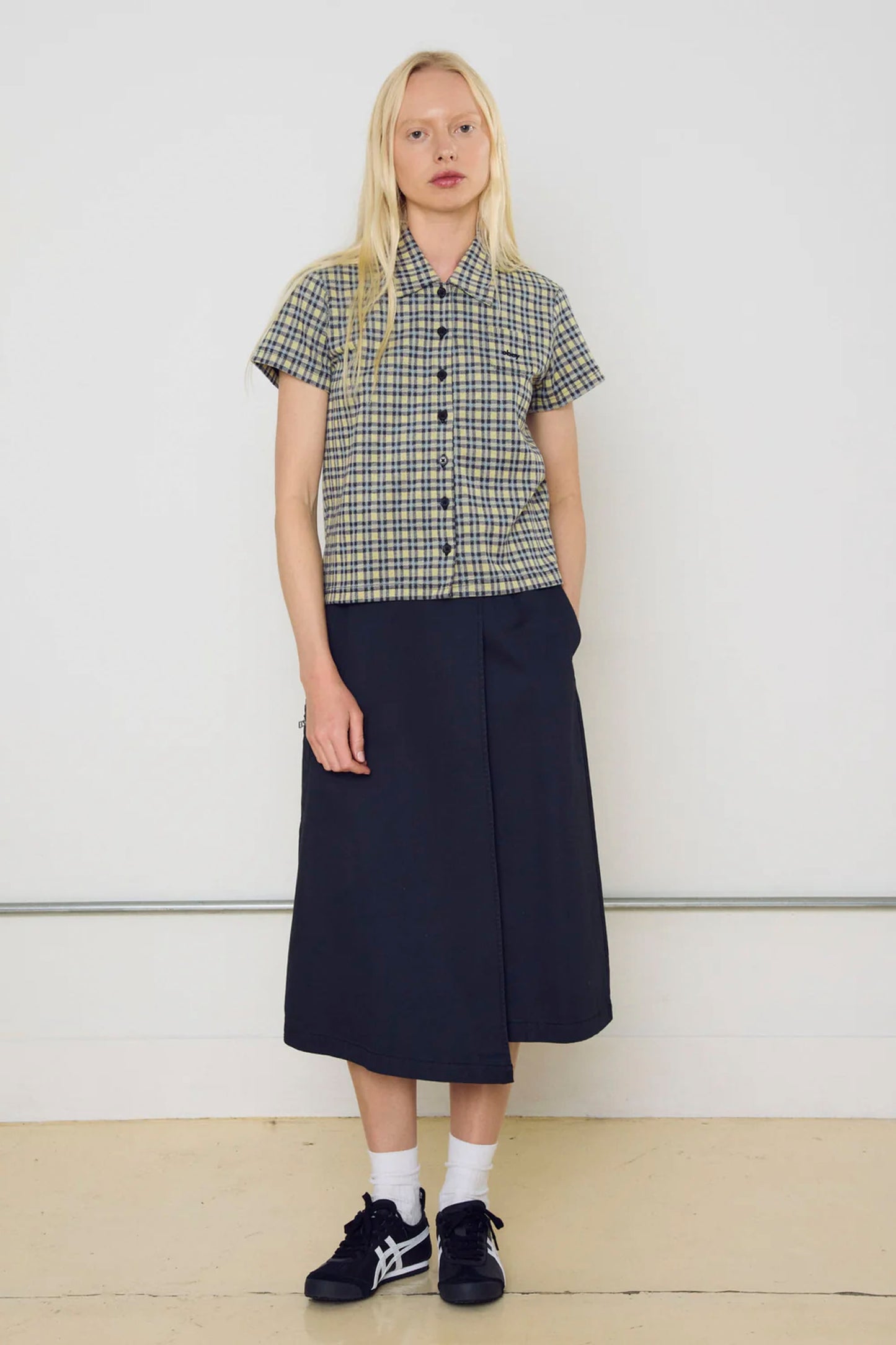 Person wearing a checkered Obey Lila Micro shirt and navy skirt against a white background