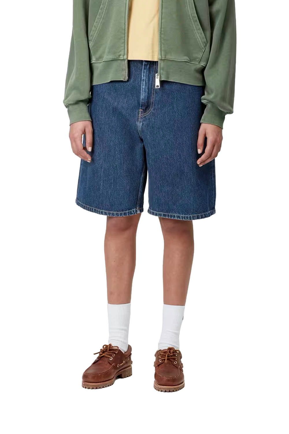 Person wearing blue denim shorts, green jacket, and brown shoes on a white background