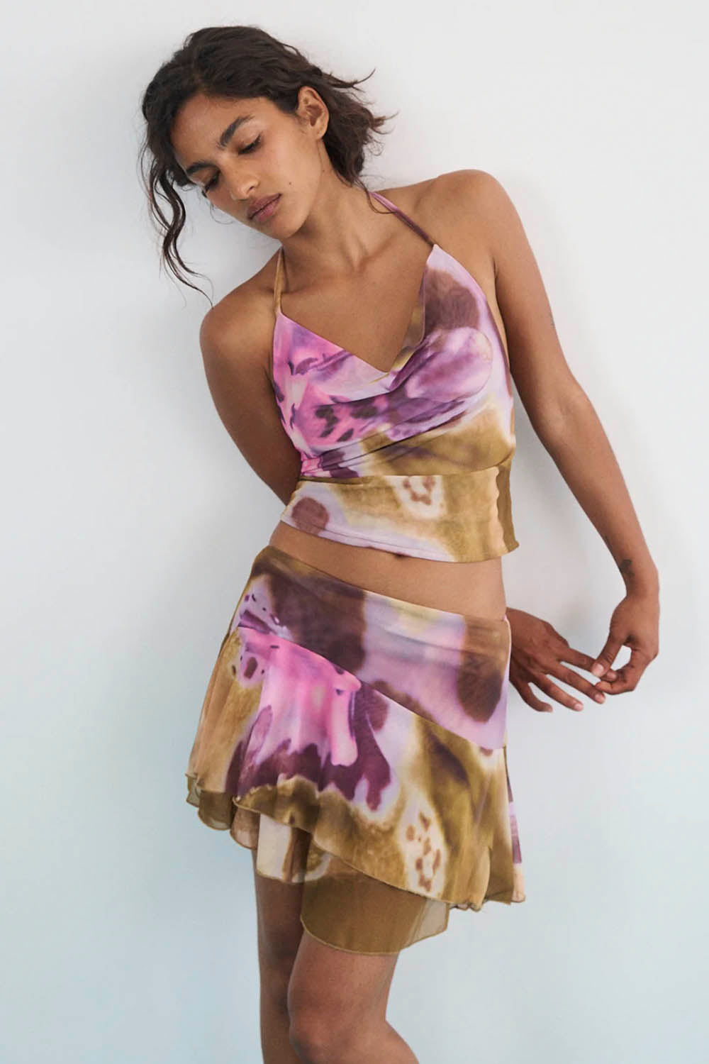 Woman wearing a colorful top and skirt with a white background