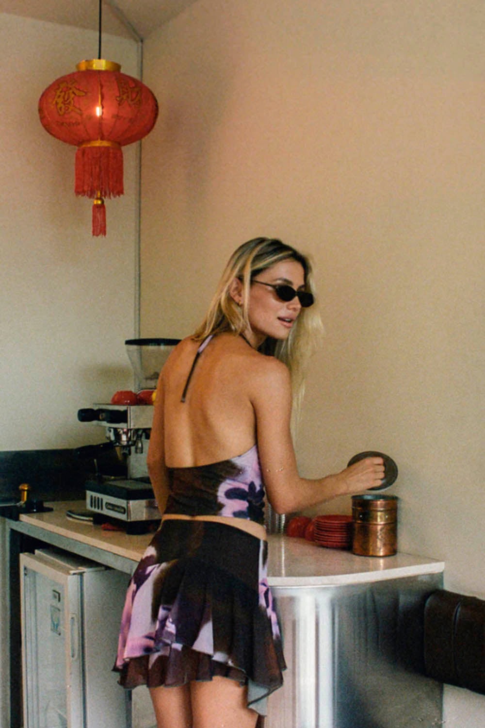 Woman wearing a black and purple top and skirt with floral patterns in an indoor setting.