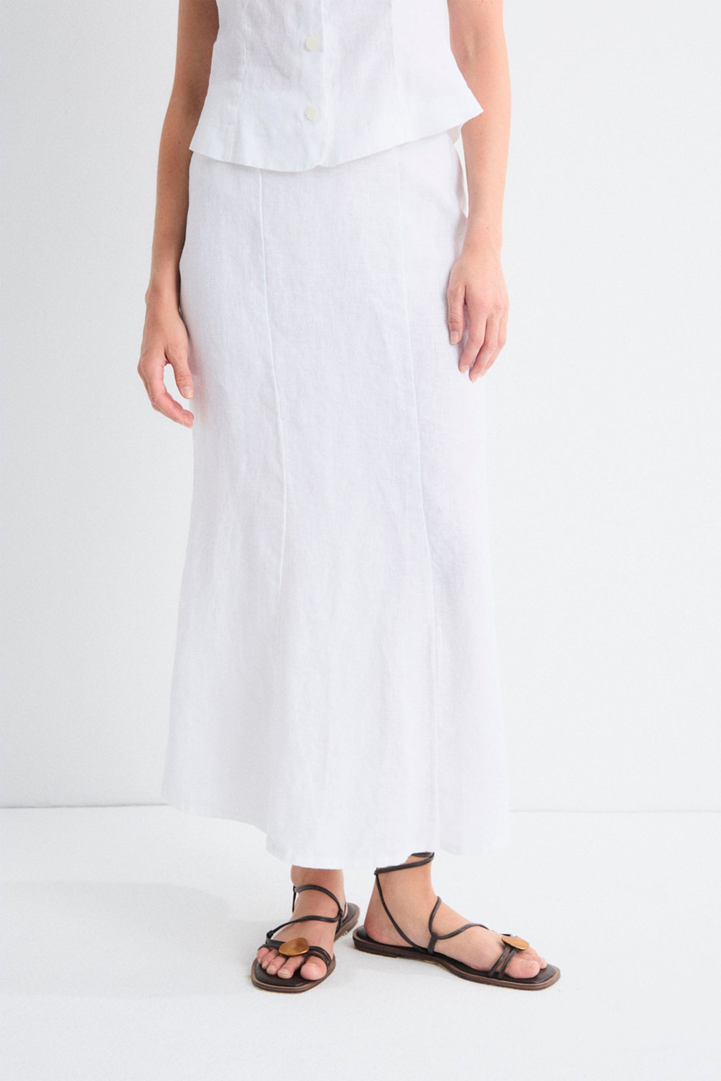 Person wearing a white outfit with black sandals on a white background