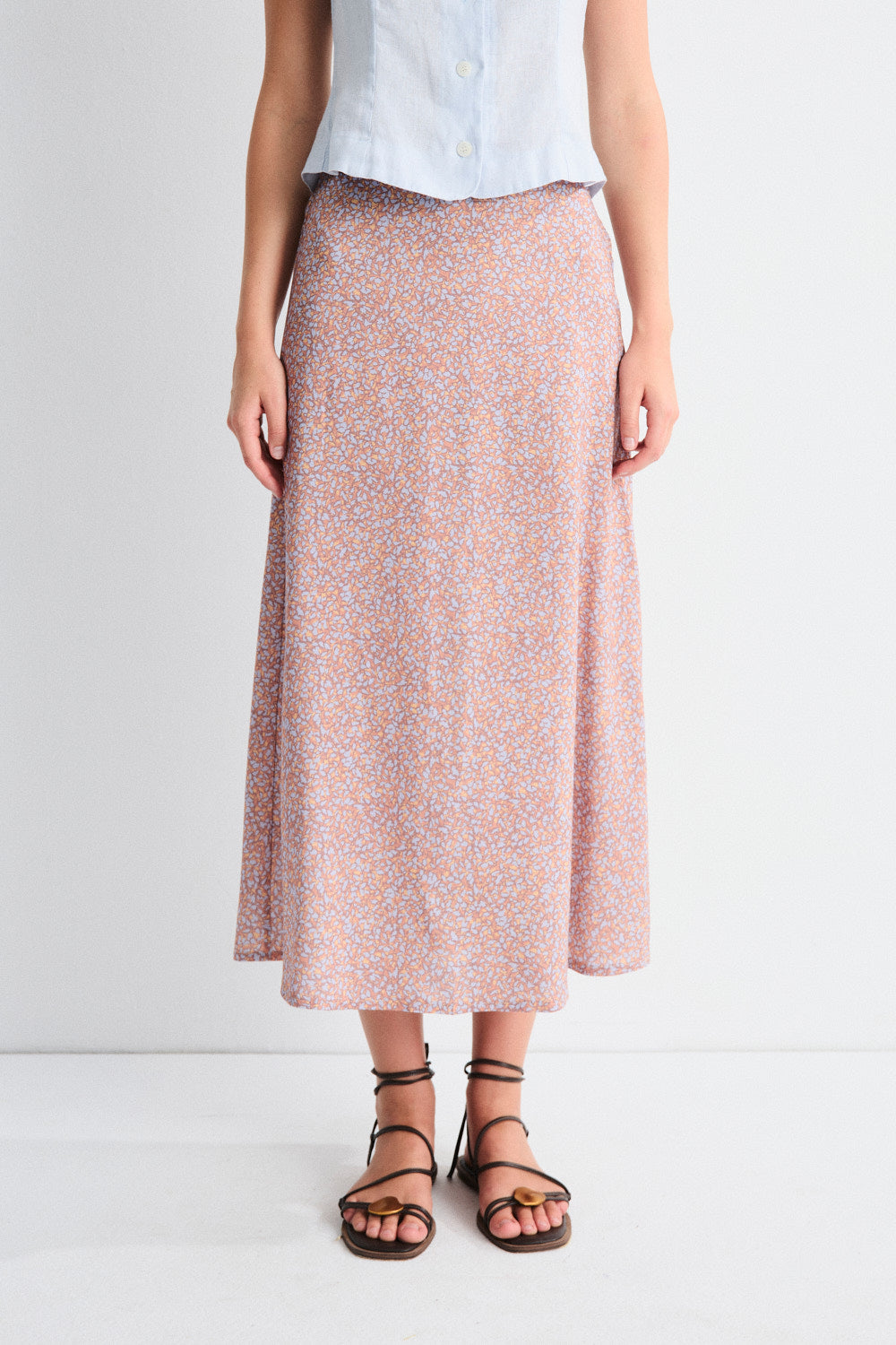 Person wearing a patterned skirt and white top on a plain background