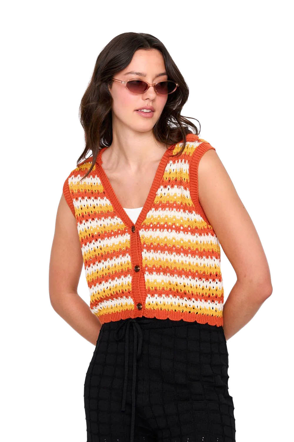 Woman wearing a colorful striped sleeveless sweater on a white background