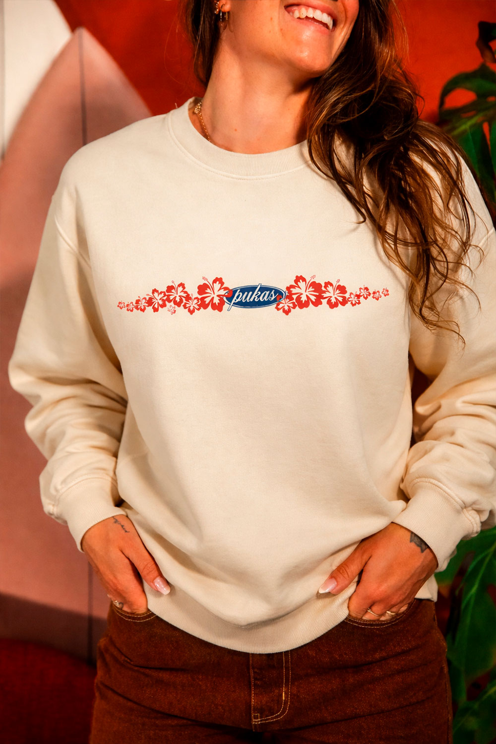 Person wearing a beige sweatshirt with floral design and 'pukas' logo.
