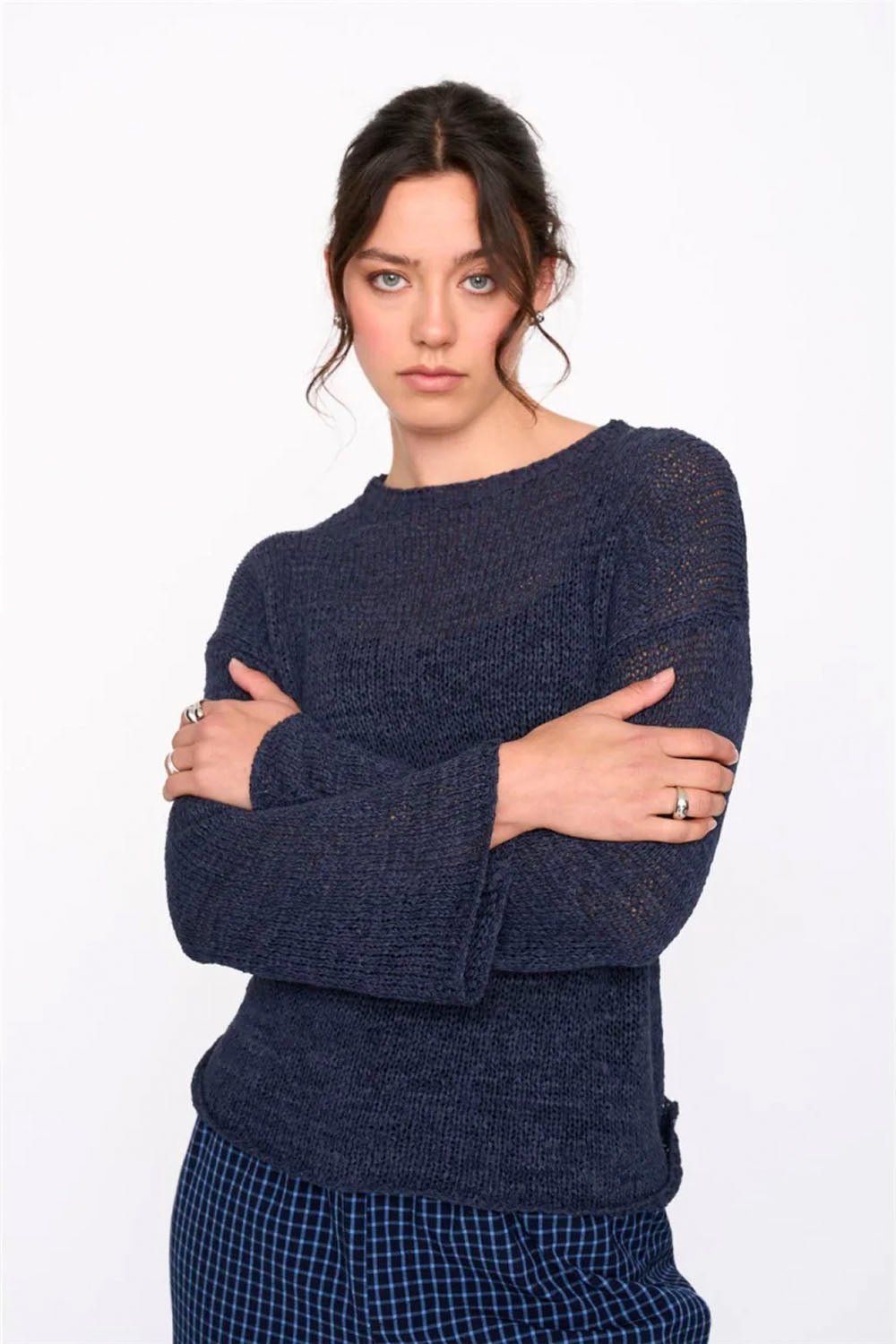 Woman wearing a dark blue sweater with checkered pants on a white background