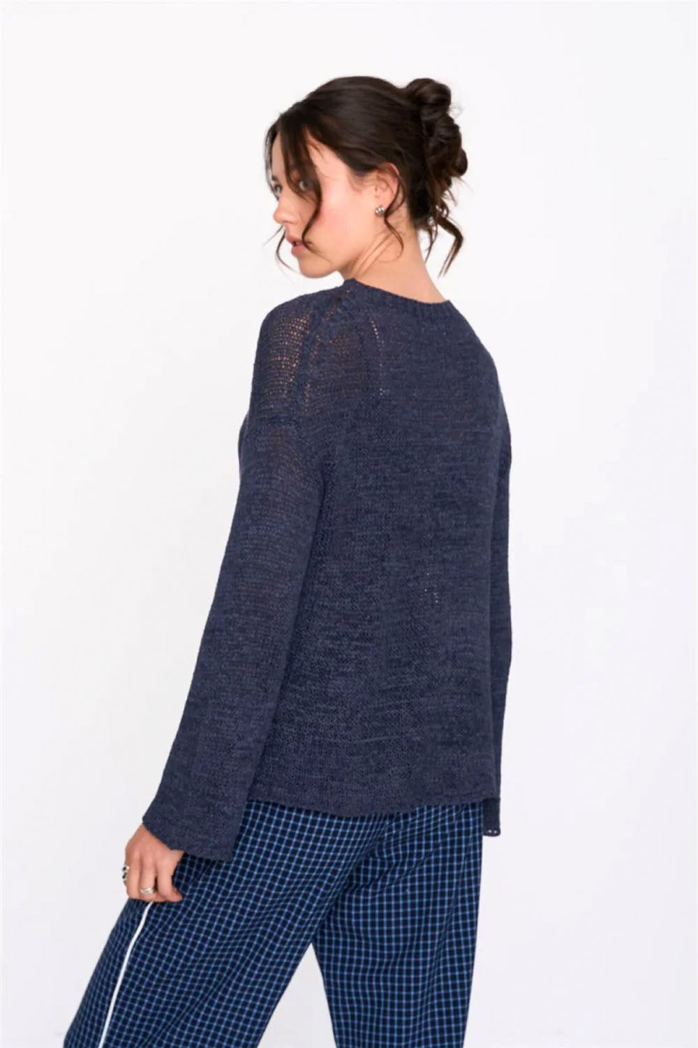 Woman wearing a dark blue sweater and checkered pants on a white background