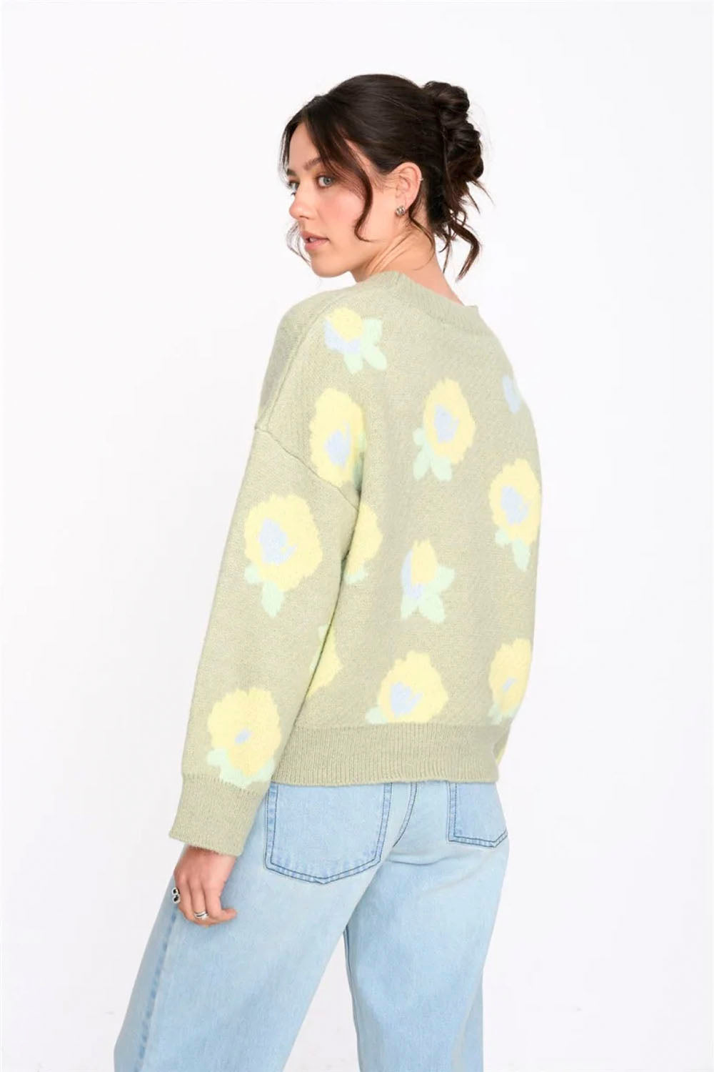 Woman wearing a light green sweater with sunflower patterns on a white background