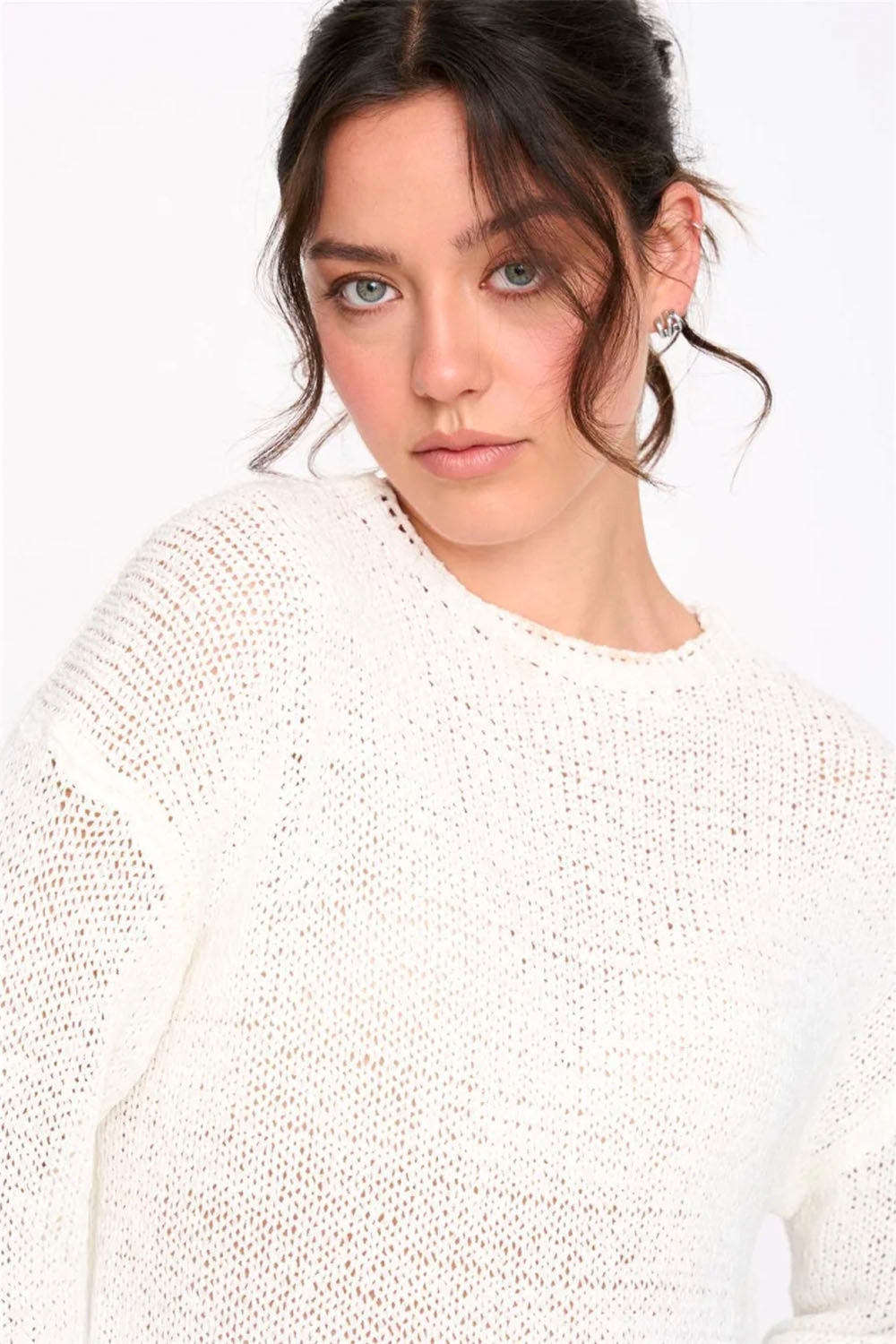 Woman wearing a white textured sweater against a plain background