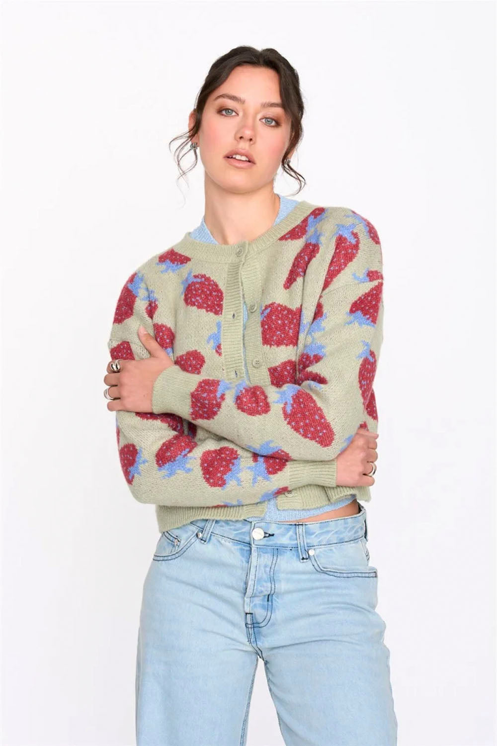 Woman wearing a patterned sweater and light blue jeans on a white background