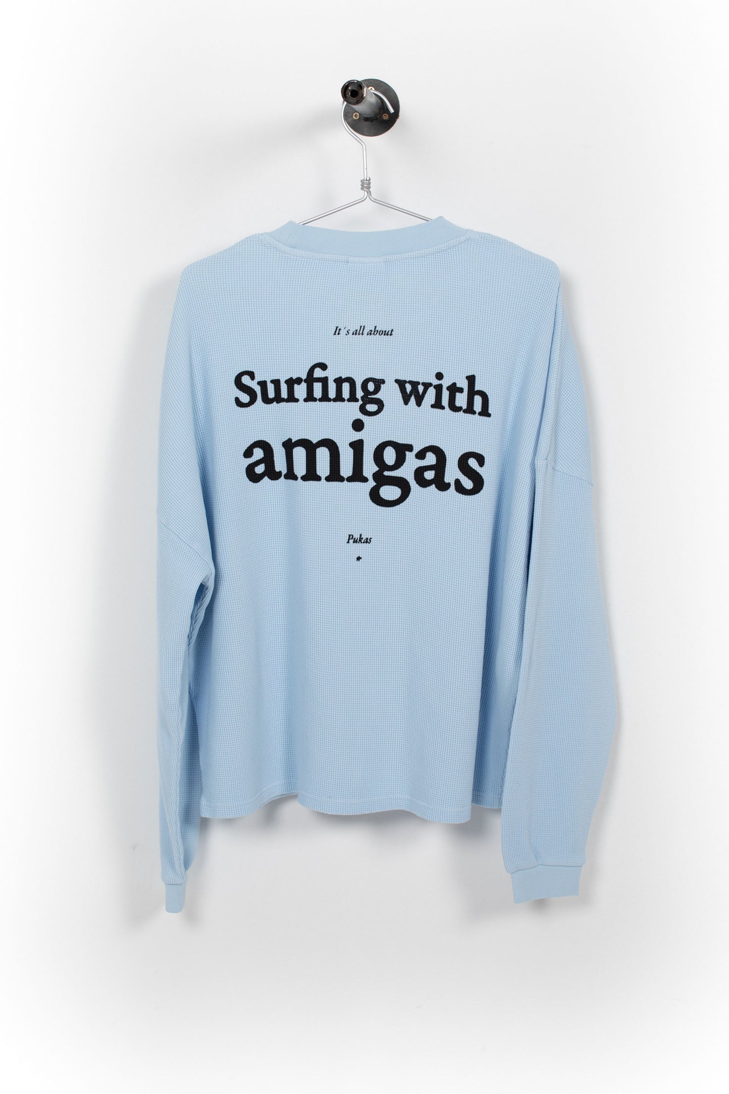 Light blue long-sleeve shirt with text 'Surfing with amigas' on a white background