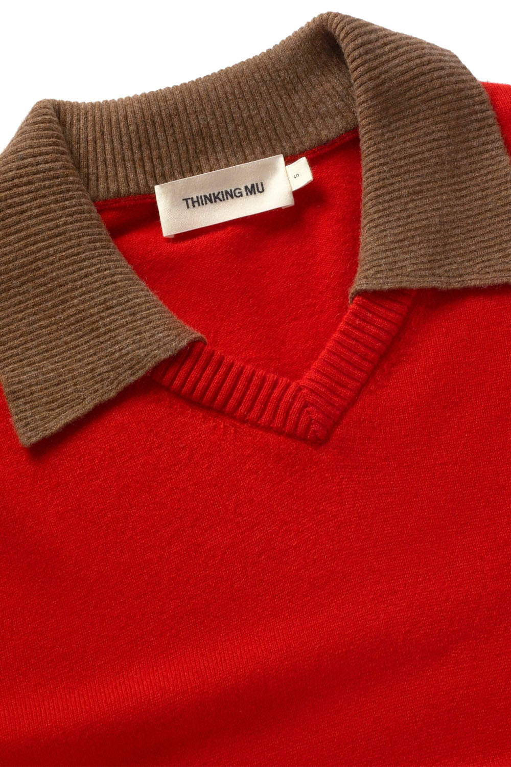 Close-up of a red knit sweater with a ribbed brown collar, showing the brand label 'THINKING MU'.