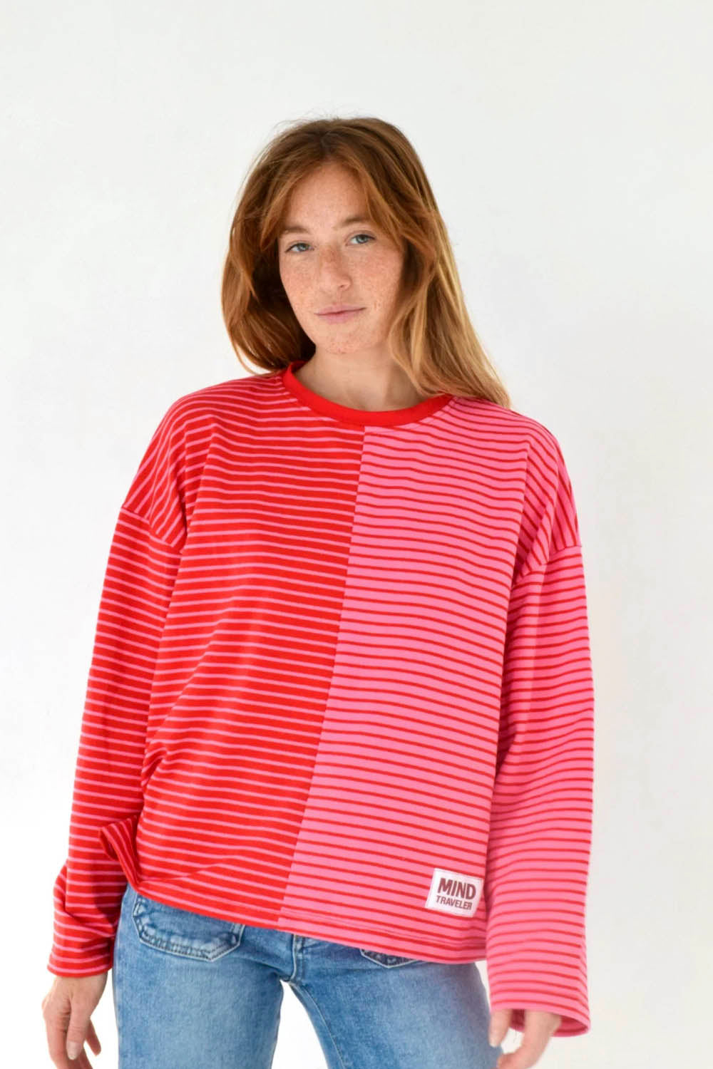 Mind Traveler BCN Mariona Long Sleeve Tee Red Pink — women's relaxed-fit bicolour striped long sleeve tee with red ribbed crew neck and Mind Traveler BCN label at hem, styled with blue jeans