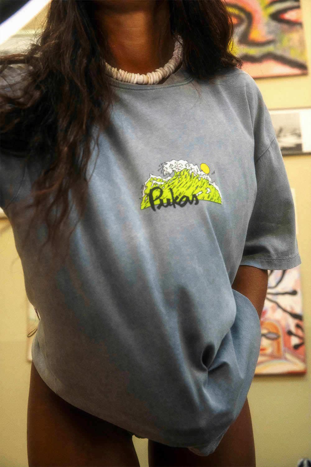 Person wearing a gray t-shirt with a yellow logo in an indoor setting