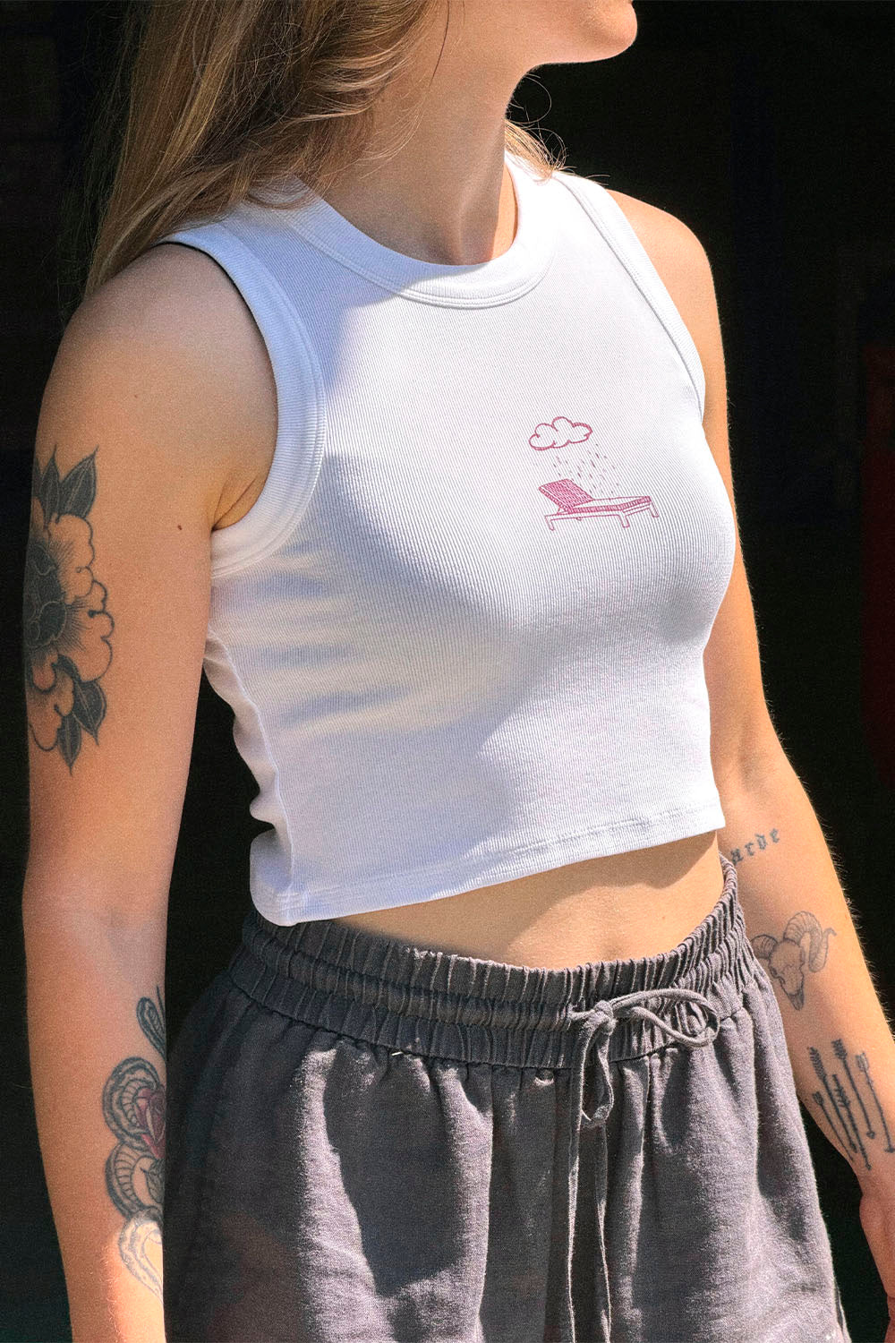Person wearing a white tank top with a graphic design on a dark background