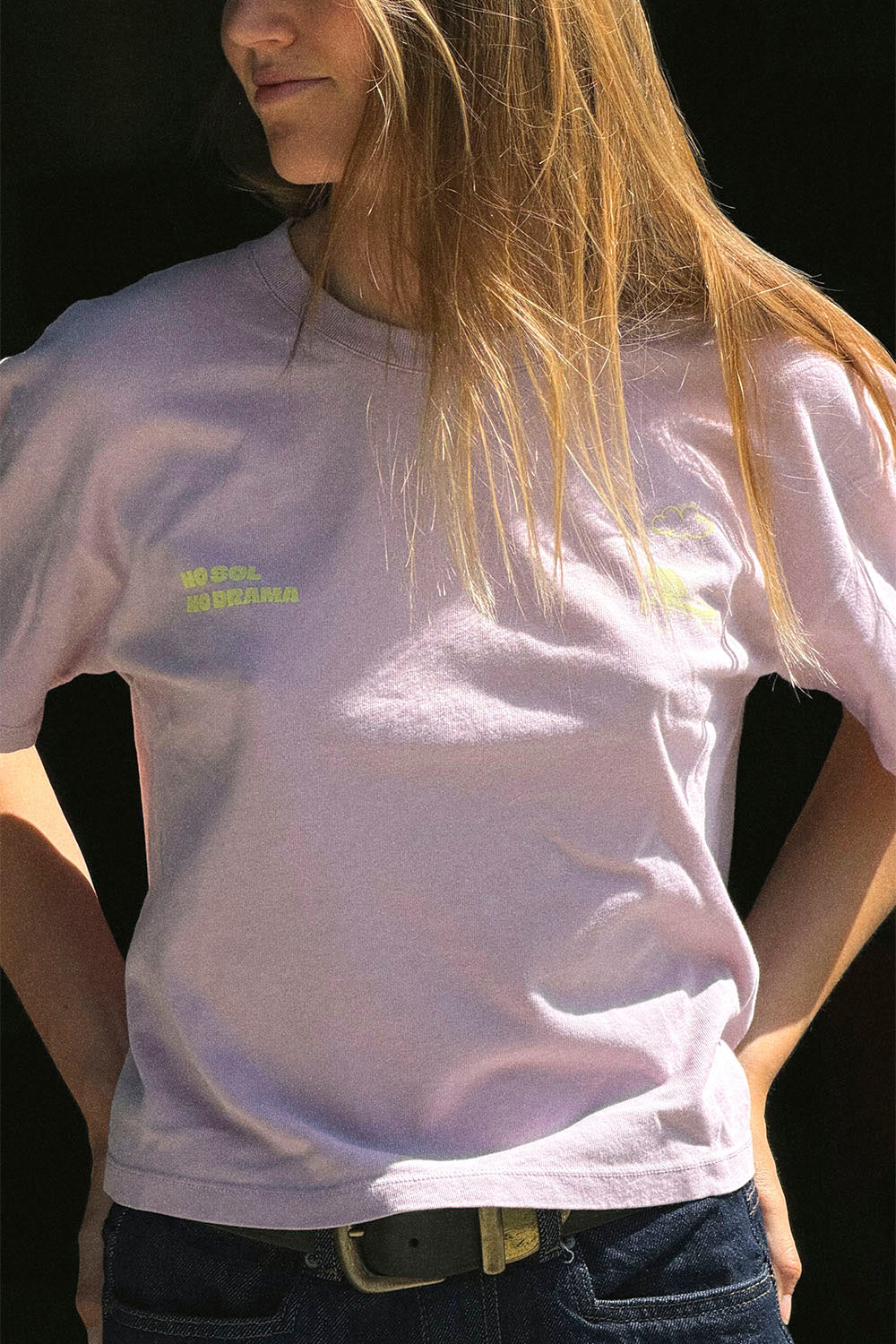 Person wearing a light purple t-shirt with text on it against a black background