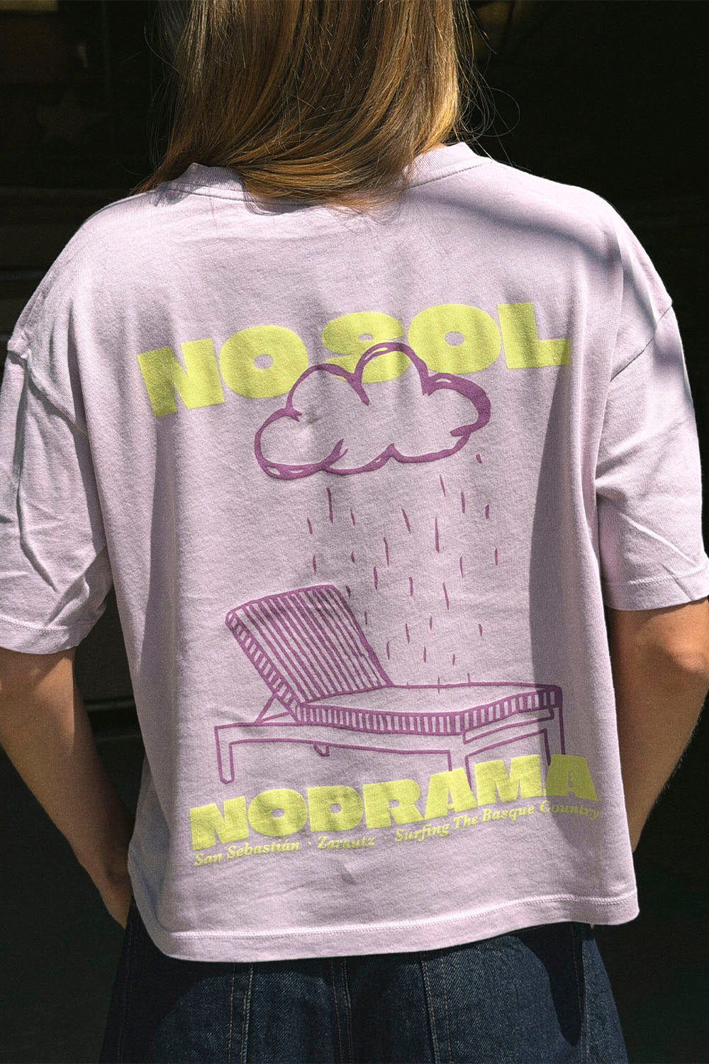 Person wearing a t-shirt with a graphic design on the back, featuring text and a cloud with a chair.
