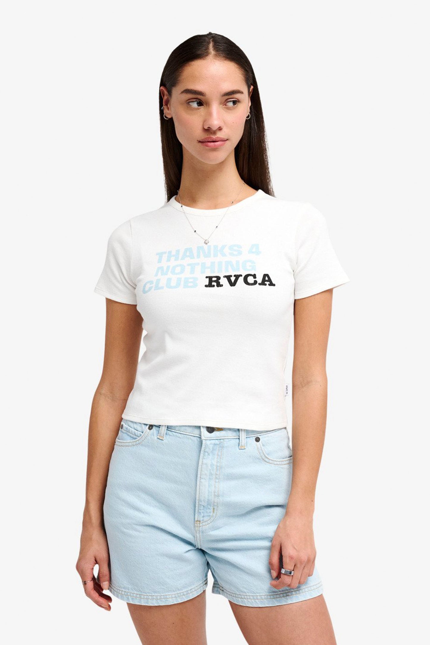 Woman wearing a white RVCA Smiley Tank and light blue denim shorts on a white background