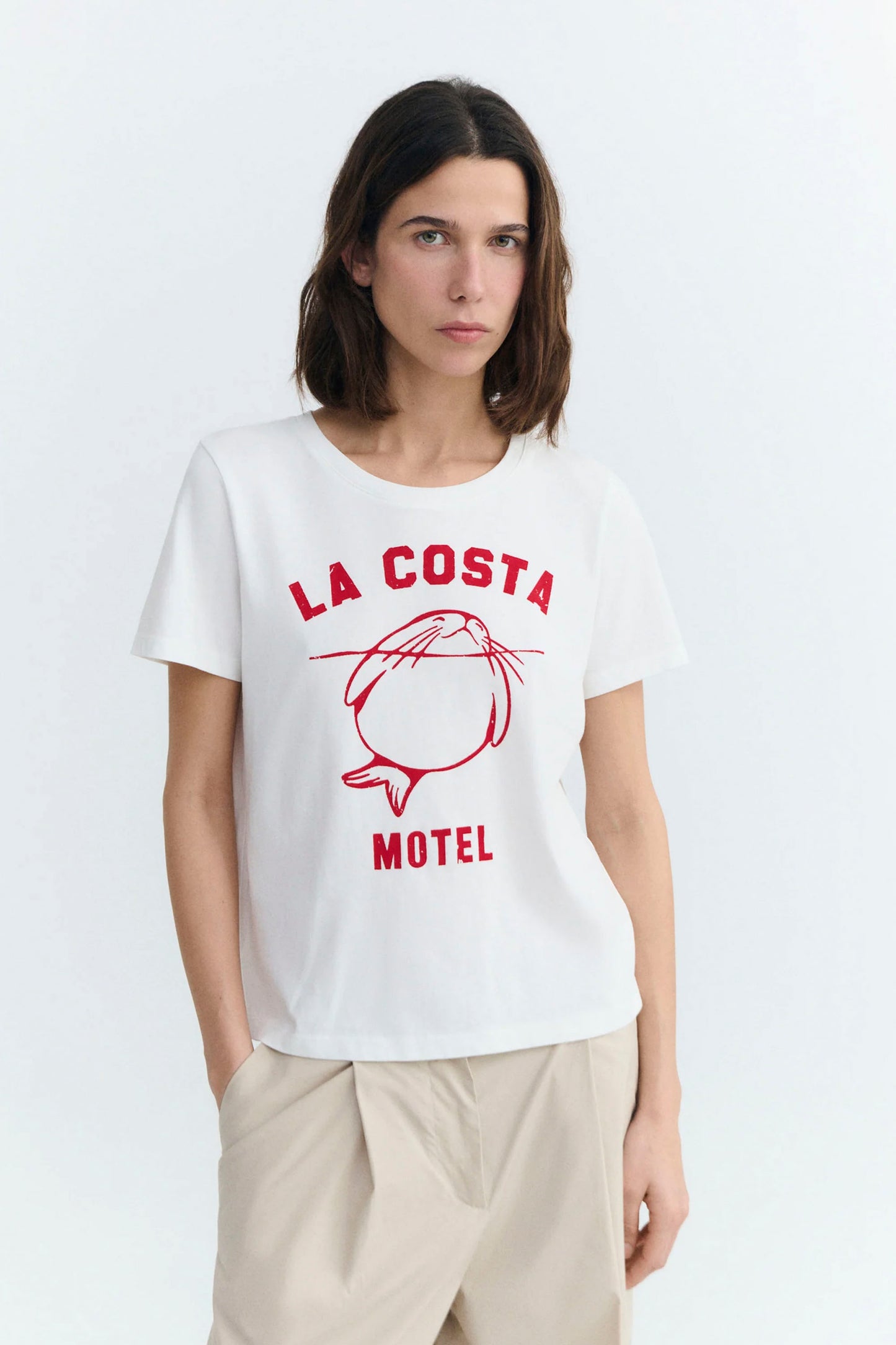 Person wearing a white Thinking Mu t-shirt with red text and graphic design on a plain background