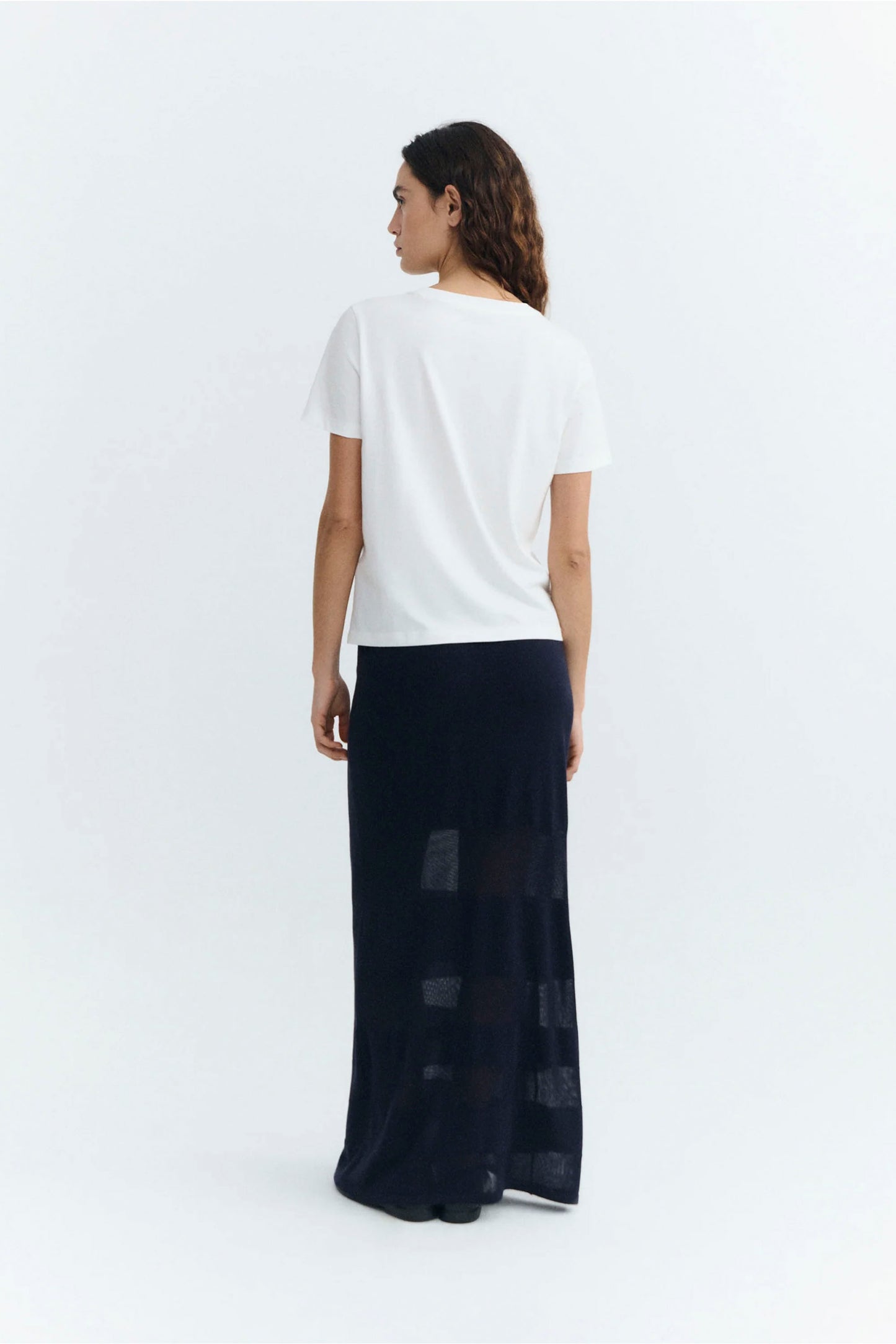 Woman wearing a white Thinking Mu Blurry Cherry t-shirt and black skirt on a white background