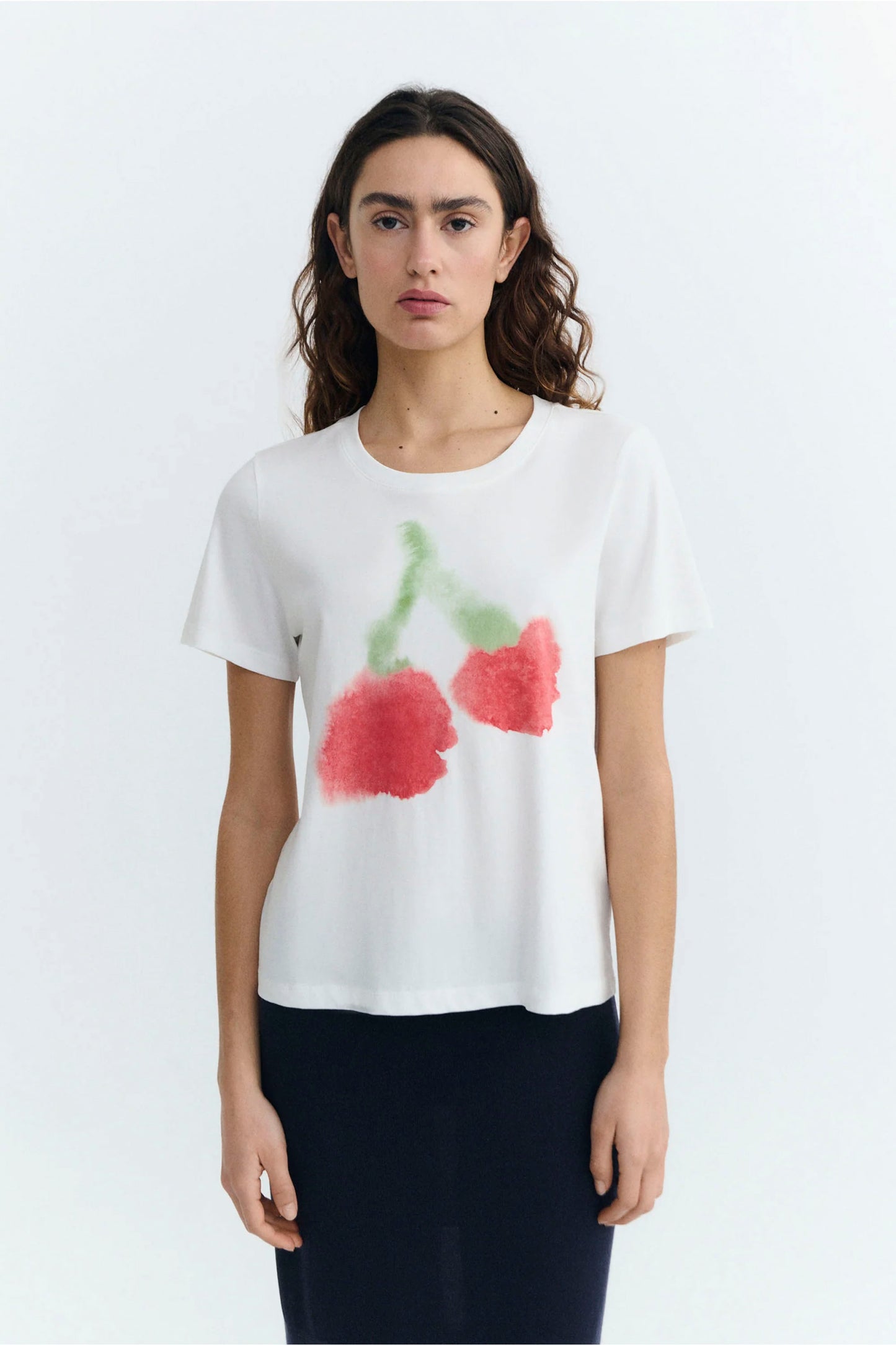 Woman wearing a white Thinking Mu Blurry Cherry t-shirt with red cherry design on a white background