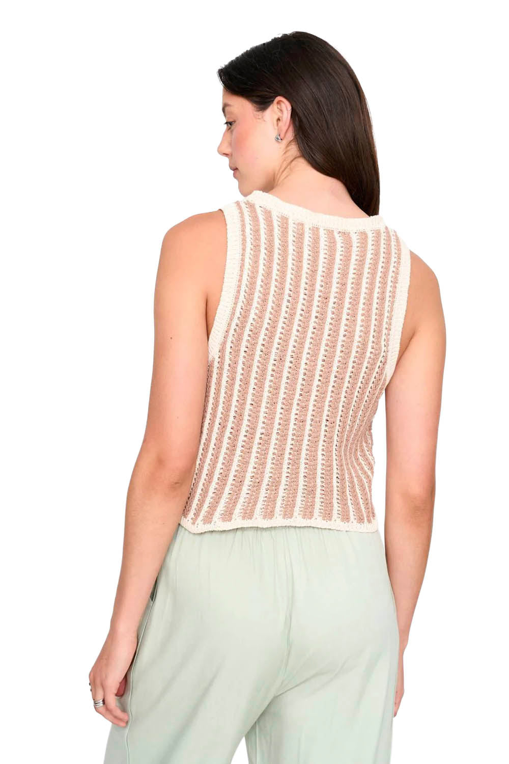 Woman wearing a beige sleeveless knitted top and light green pants on a white background