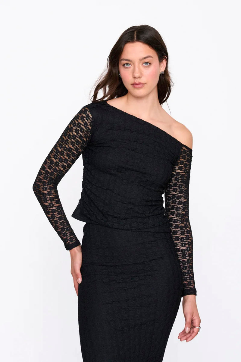 Woman wearing a black off-shoulder dress with lace sleeves on a white background