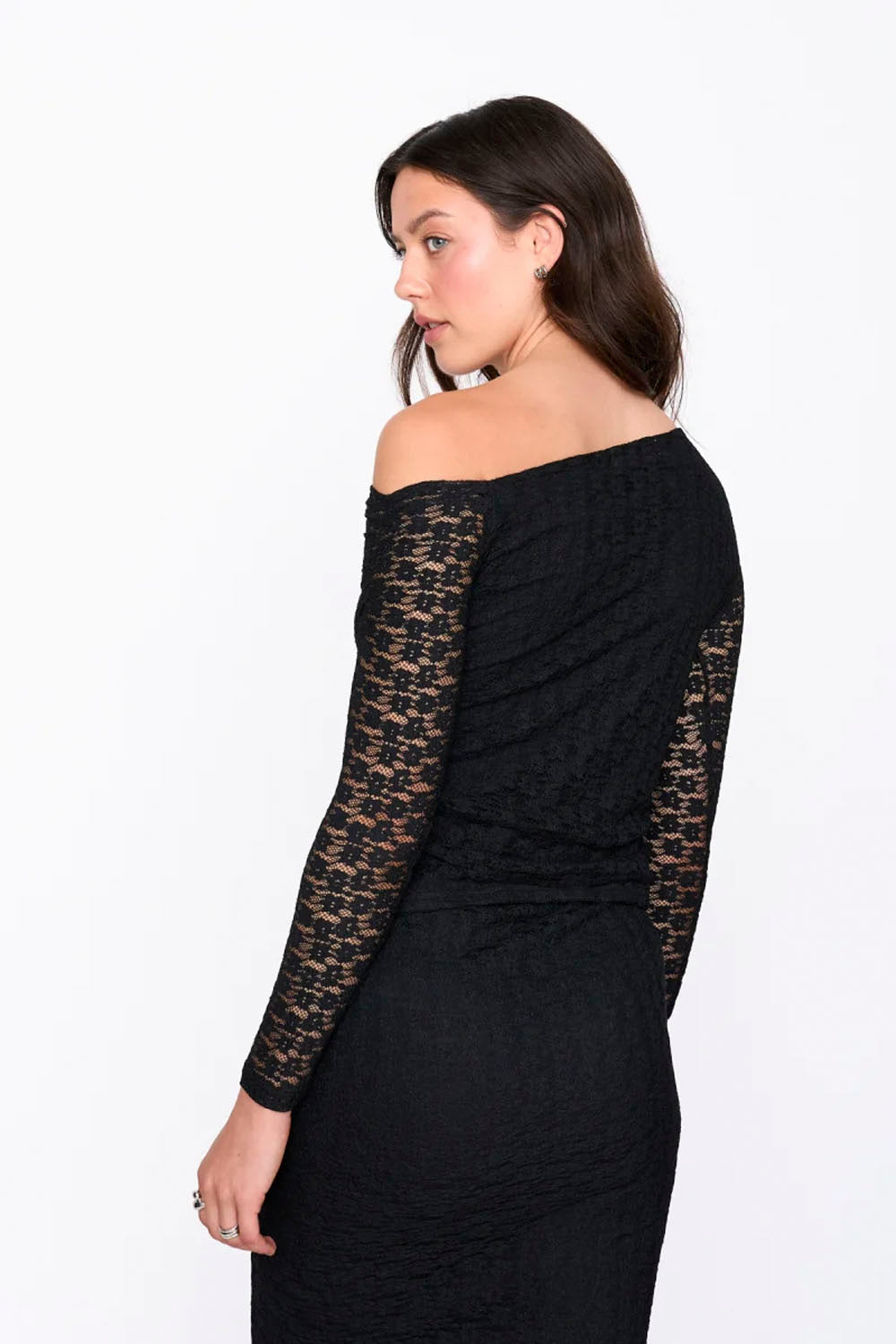 Woman wearing a black off-shoulder dress with lace sleeves on a white background