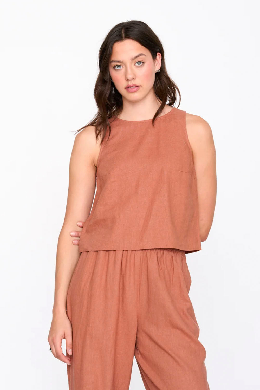 Woman wearing a brown sleeveless top and pants on a white background