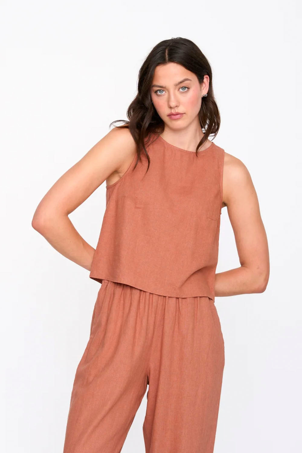 Woman wearing a brown sleeveless top and pants on a white background