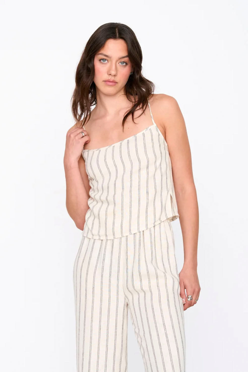 Woman wearing a white and beige striped jumpsuit on a white background