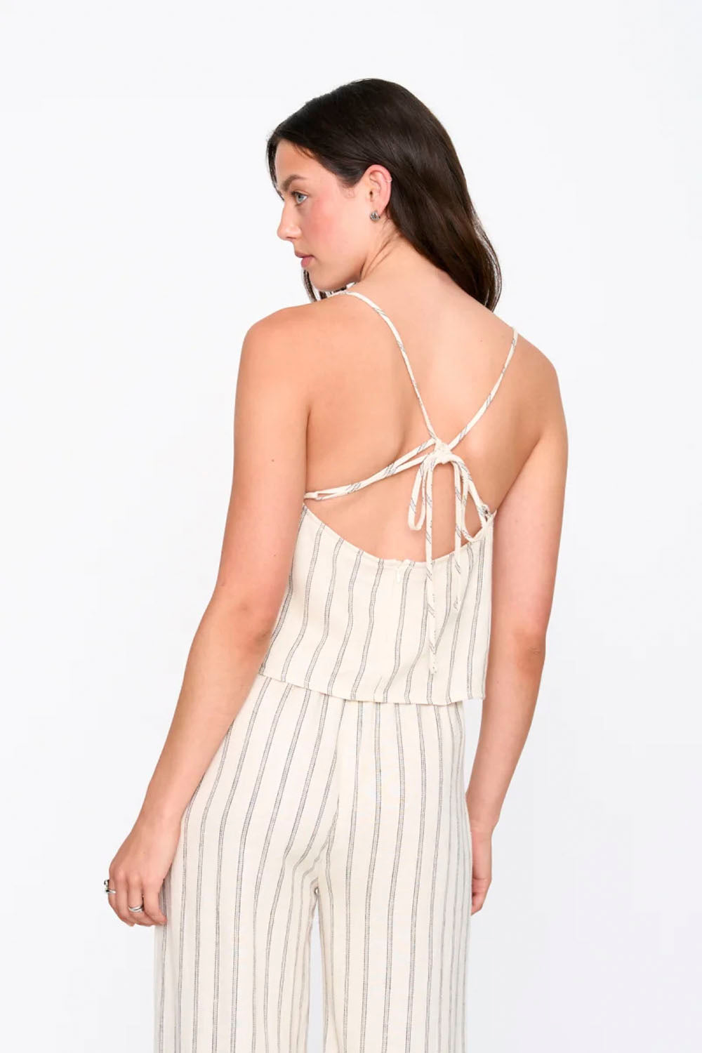 Woman wearing a white and beige striped jumpsuit on a white background