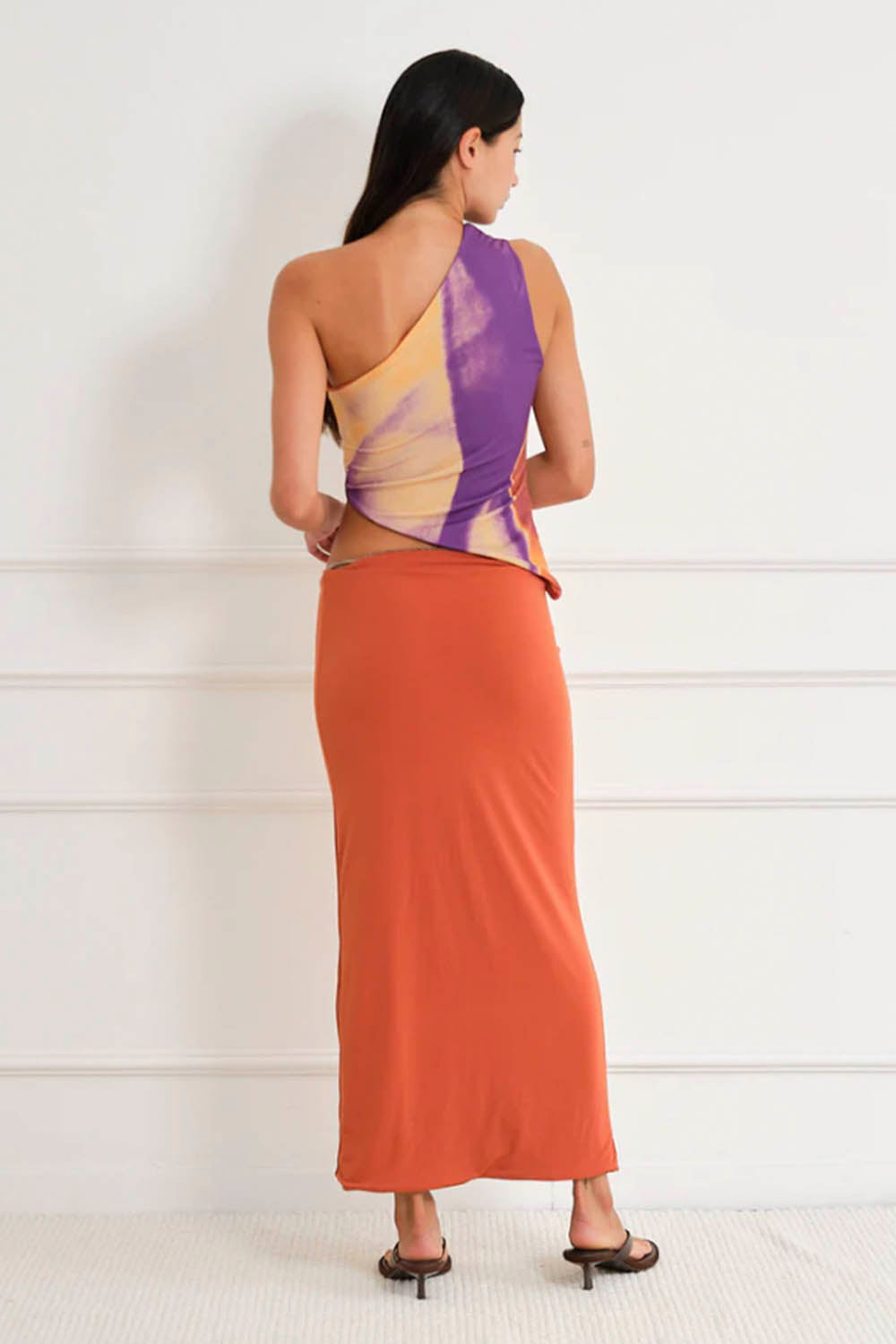 Woman wearing a tie-dye tank asymmetric top against a plain background