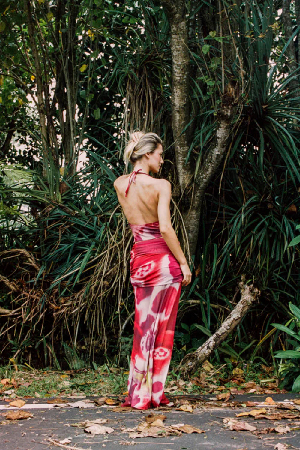 Woman in a red floral top and skirt standing in a forest setting